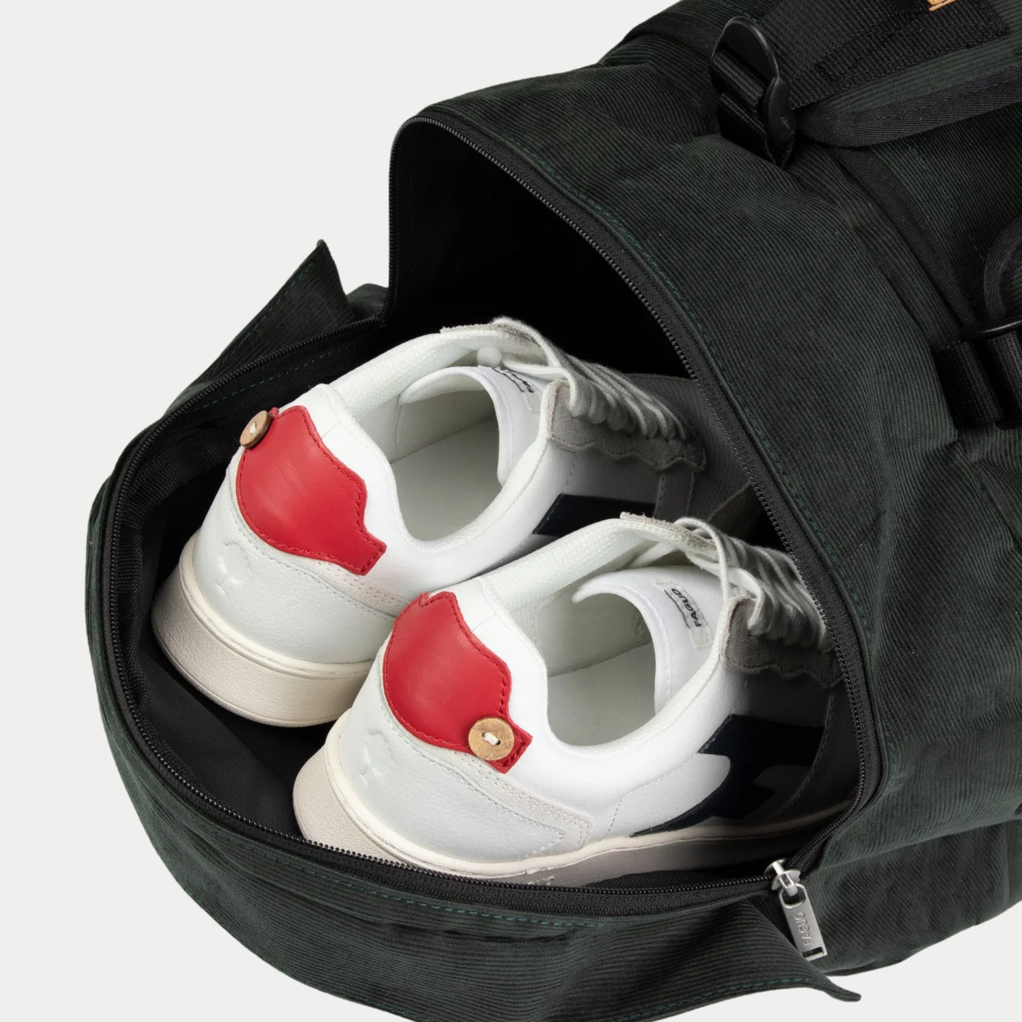 Compartiment chaussures latéral zippé du Big Duffle Faguo vert foncé, ouvert sur une paire de baskets blanches