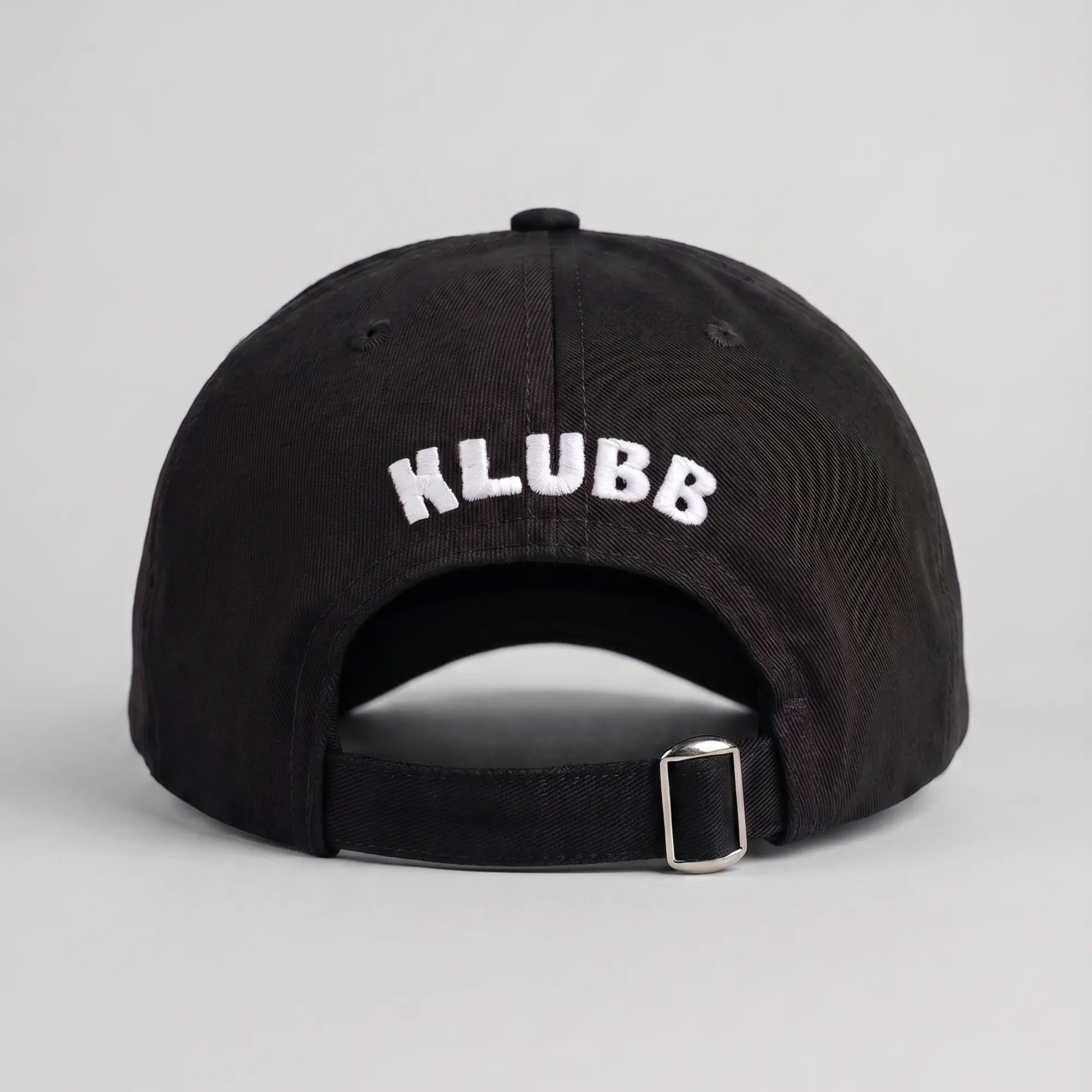 Dos de la casquette Klubb noire : lettrage KLUBB blanc brodé en arc au-dessus de la sangle et de sa boucle métal