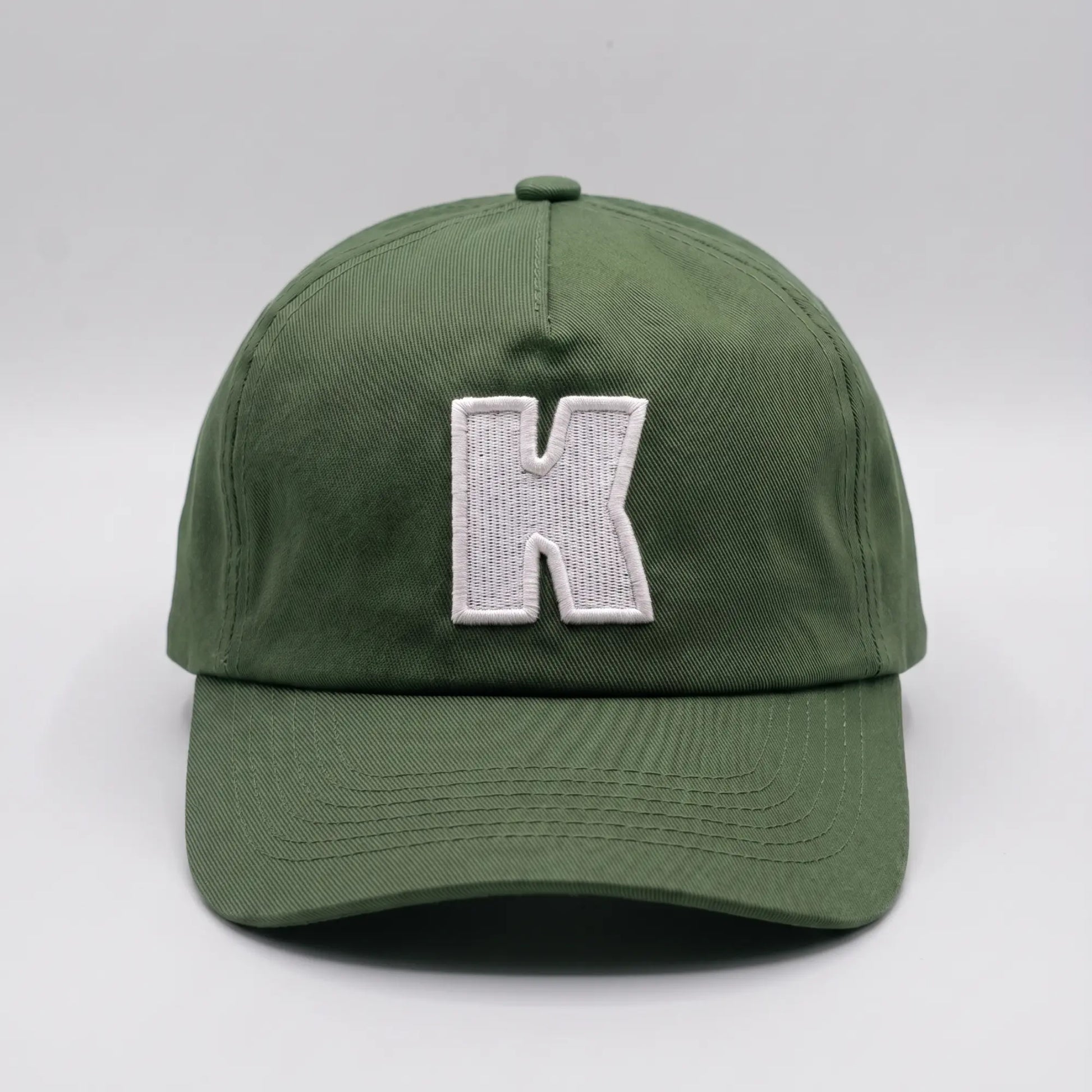Casquette baseball Klubb vert olive grisé vue de face, grand K blanc brodé au centre du panneau avant et visière courbée