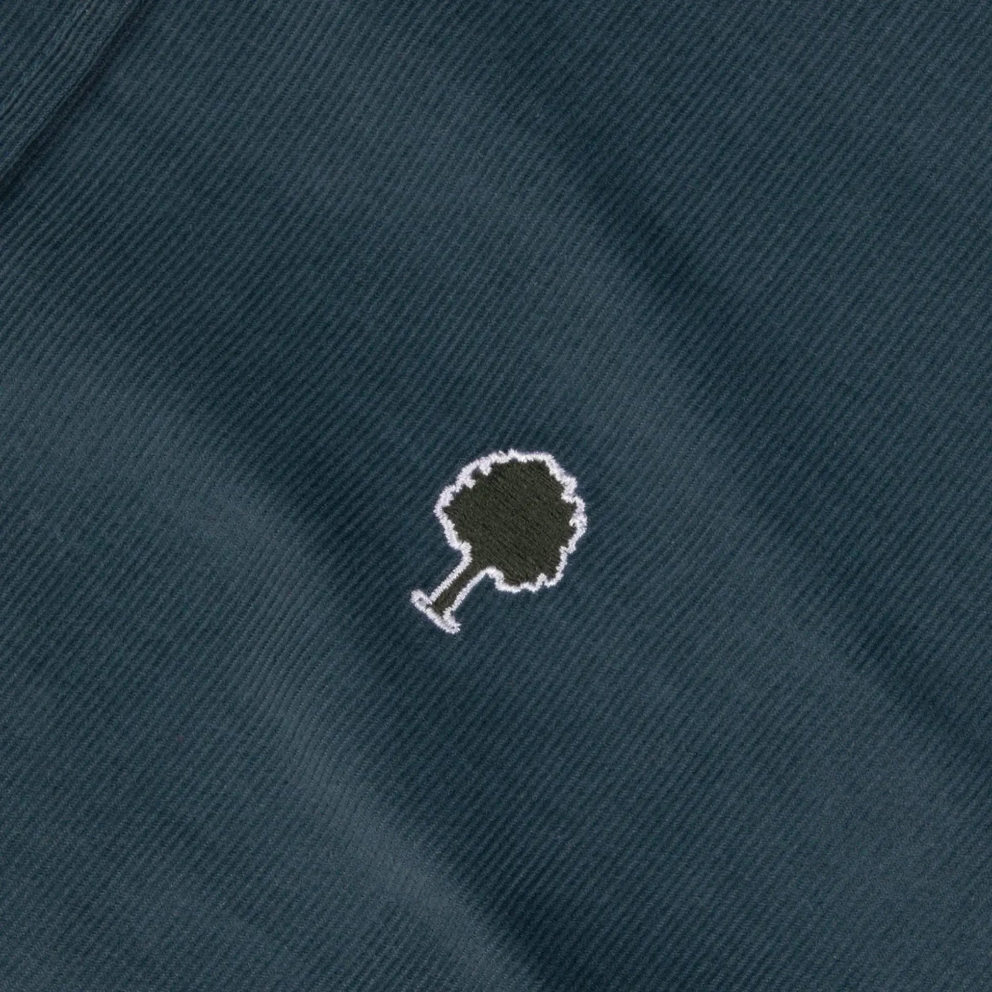 Détail du velours milleraies fin bleu pétrole de la chemise Ivoy Faguo et du logo arbre brodé kaki