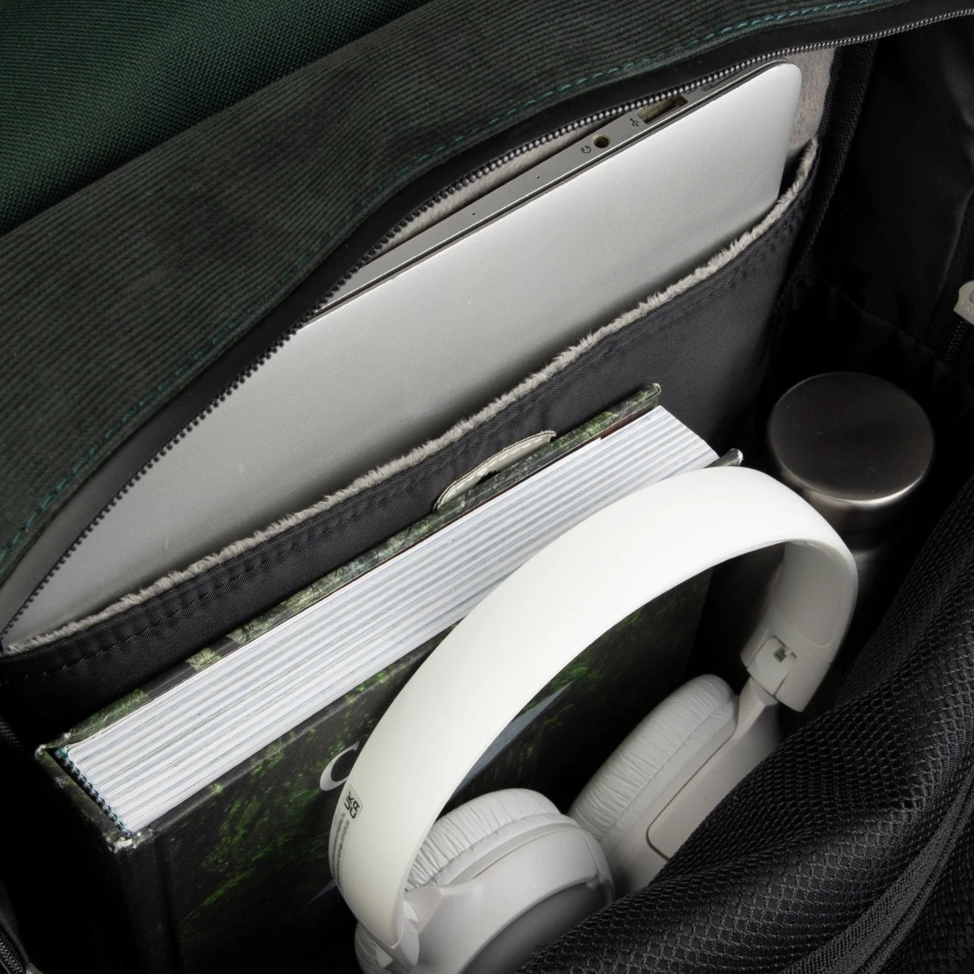 Intérieur du sac à dos Faguo Commuter 2.0 : compartiment ordinateur doublé de molleton, livre, casque audio et gourde