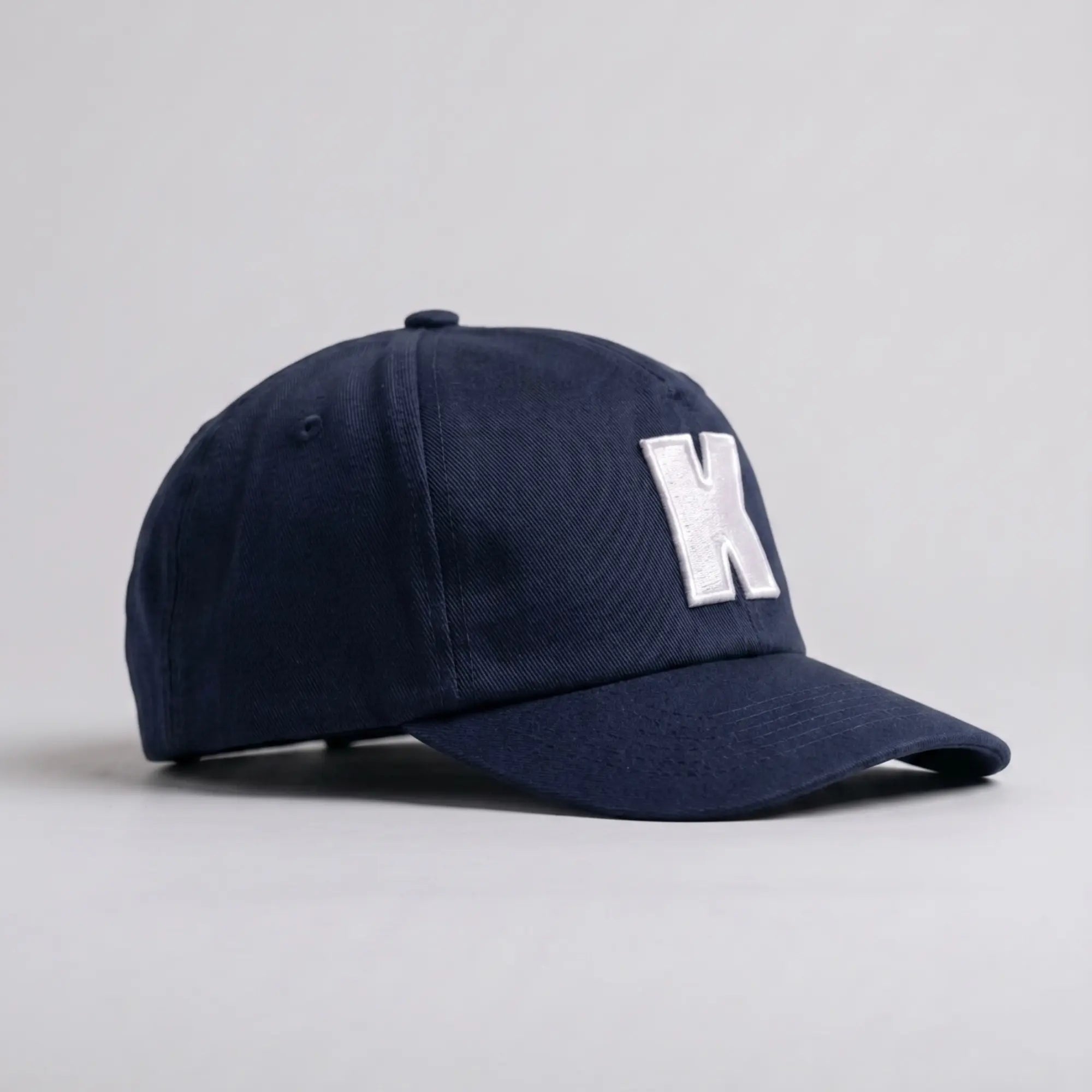 Casquette Klubb marine de trois-quarts : calotte souple sans armature, œillet d'aération brodé et visière longue à surpiqûres
