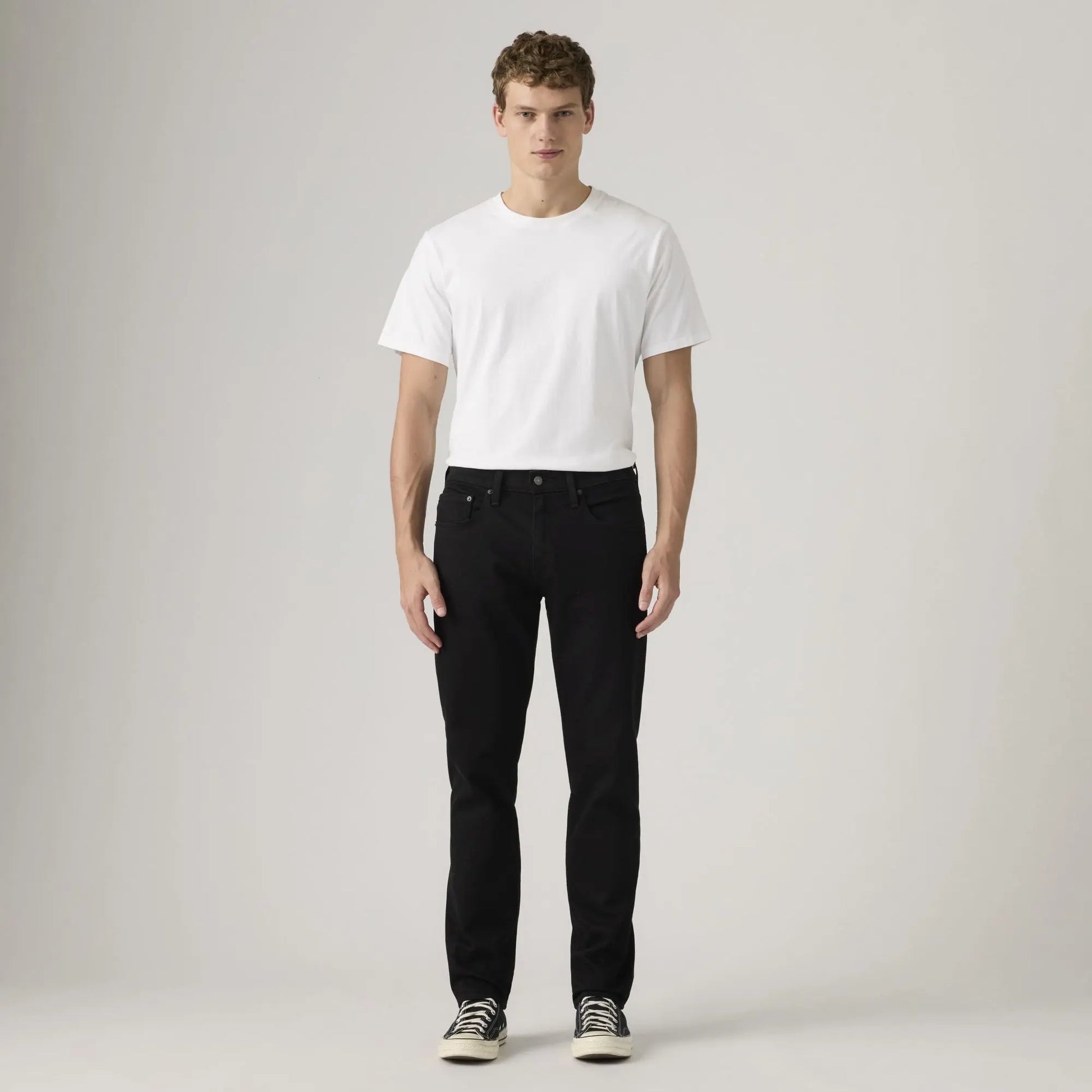 Jean Levi's 502 Taper Sta-Dark Black porté de face en silhouette plein pied avec un t-shirt blanc