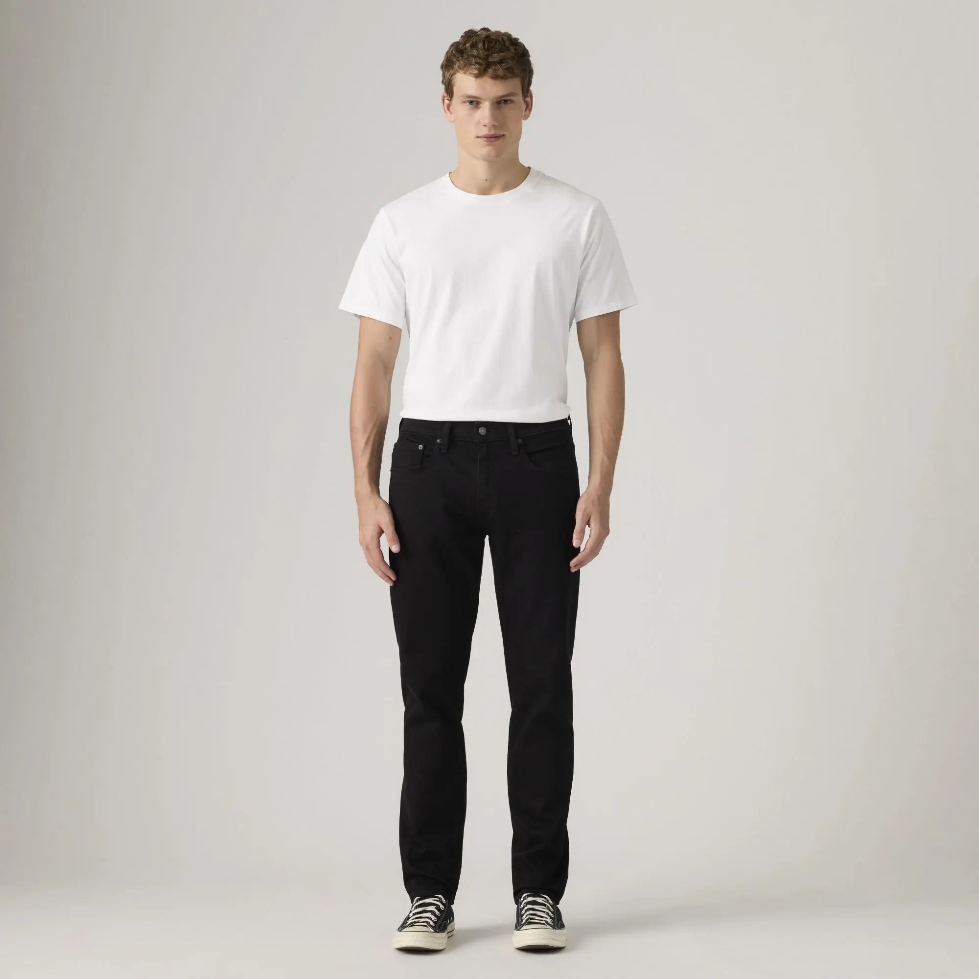 Jean Levi's 502 Taper Sta-Dark Black porté de face en silhouette plein pied avec un t-shirt blanc