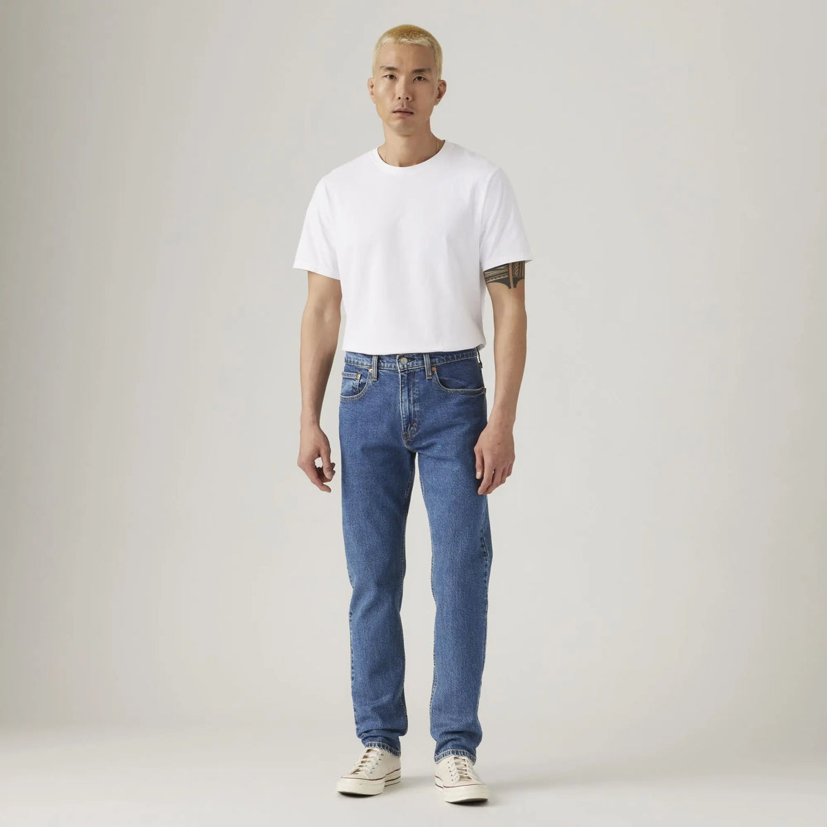 Jean Levi's 502 Taper Stonewash Stretch porté de face en pied, T-shirt blanc et baskets montantes écrues