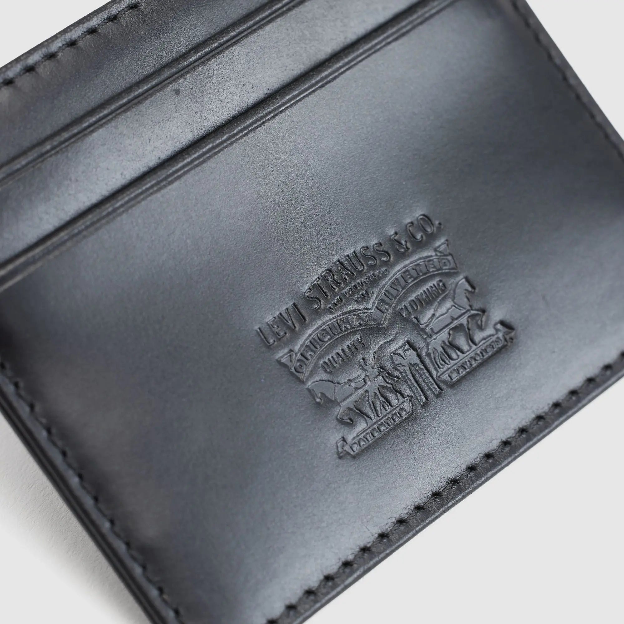 Gros plan sur le logo Two Horse Levi Strauss & Co. embossé dans le cuir noir du porte-cartes