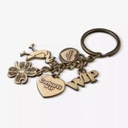 Porte-clés Charms Carhartt WIP : anneau laiton vieilli et cinq breloques gravées, trèfle, cœur, oiseau, médaillon