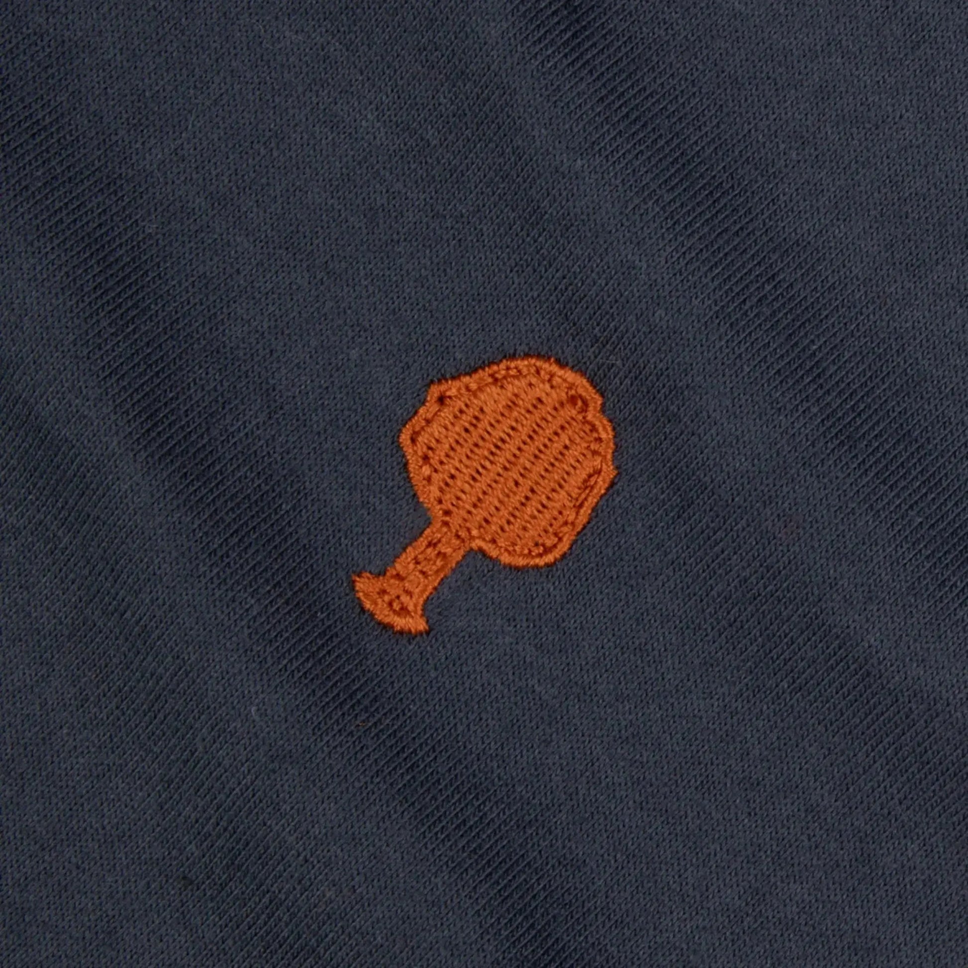 Détail macro de la broderie arbre orange sur le jersey de coton bleu marine du T-shirt Arcy Faguo