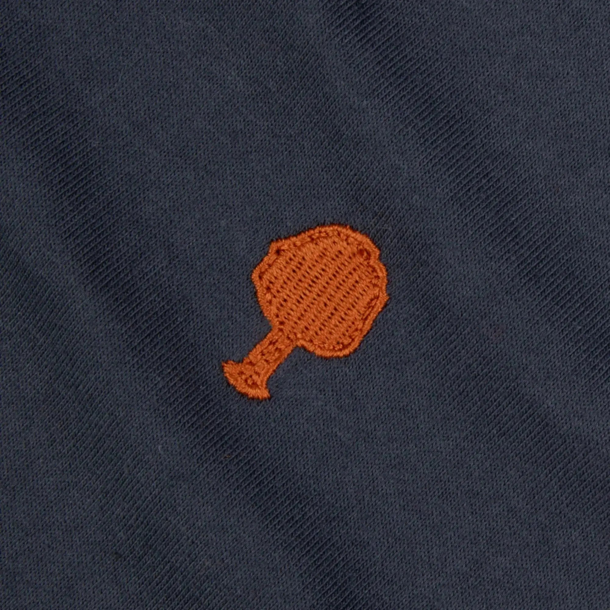 Détail macro de la broderie arbre orange sur le jersey de coton bleu marine du T-shirt Arcy Faguo
