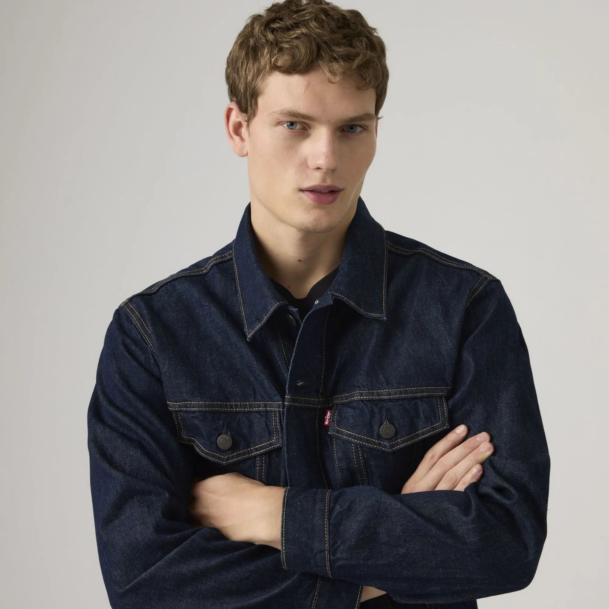 Veste Trucker Levi's Wash It Out Rinsed en gros plan buste, bras croisés, tab rouge et col pointu