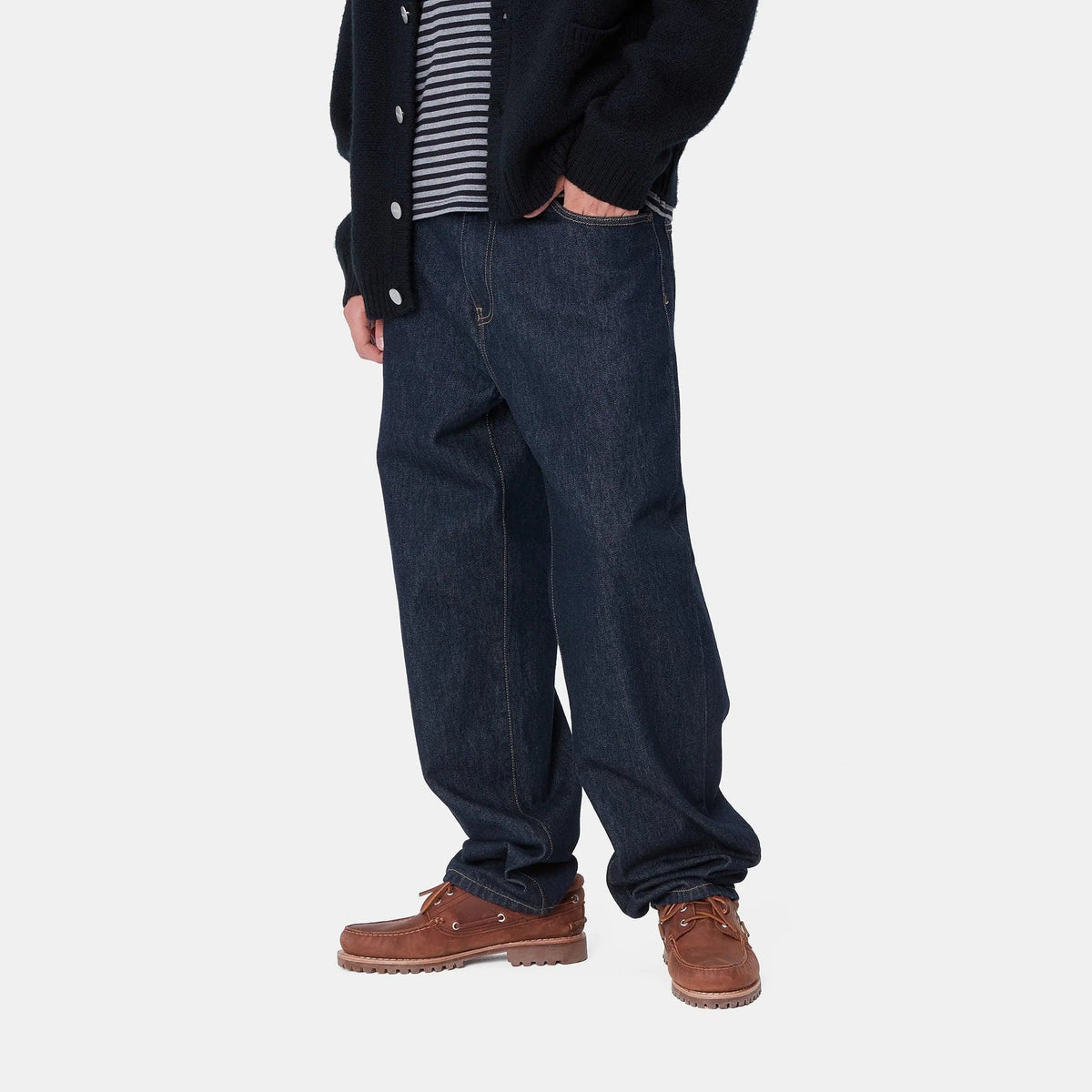Aaron Pant Blue Rinsed porté de trois quarts, indigo sombre, jambe droite ample qui casse sur la chaussure