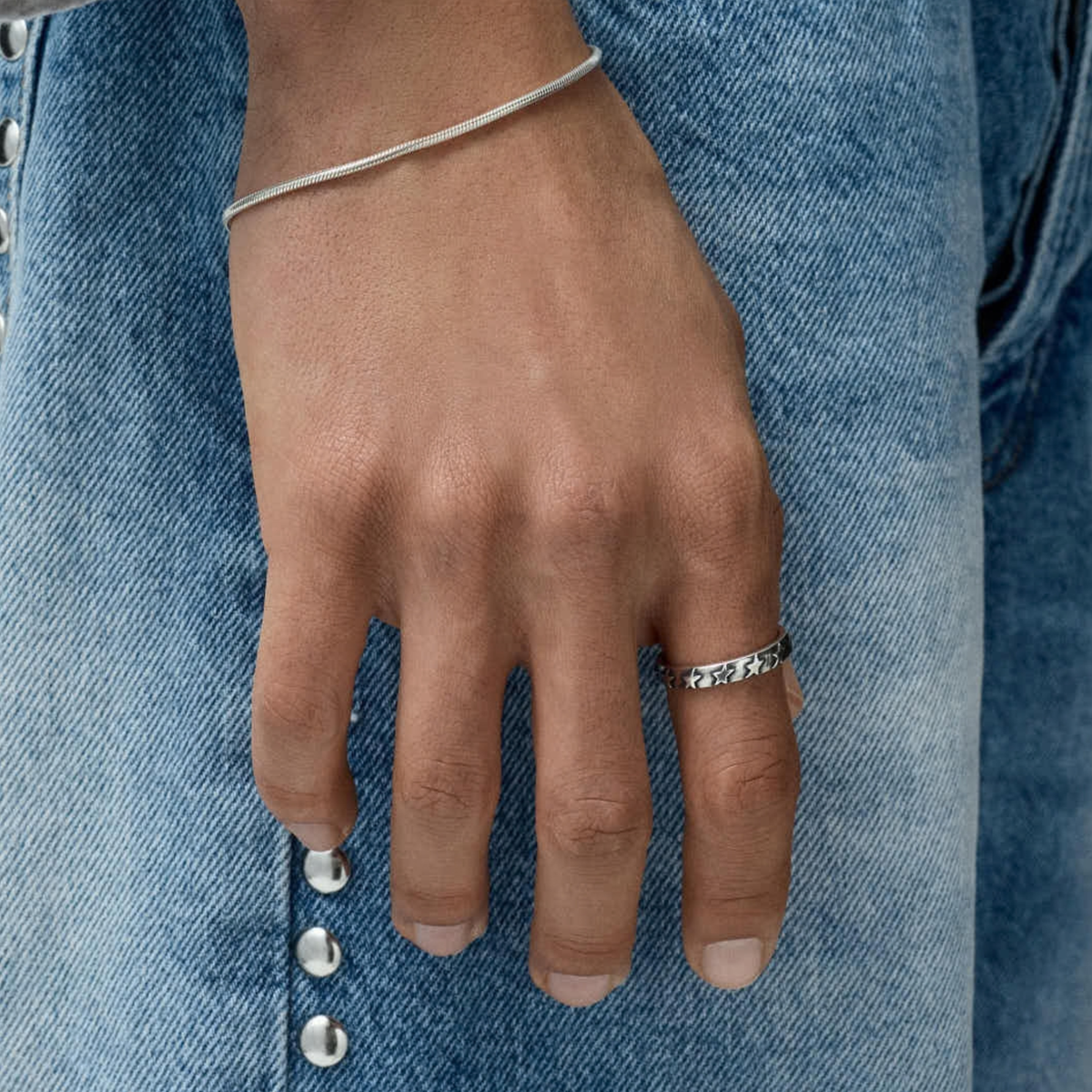 Bague Star Studded argentée Twojeys portée à la main, sur un jean bleu