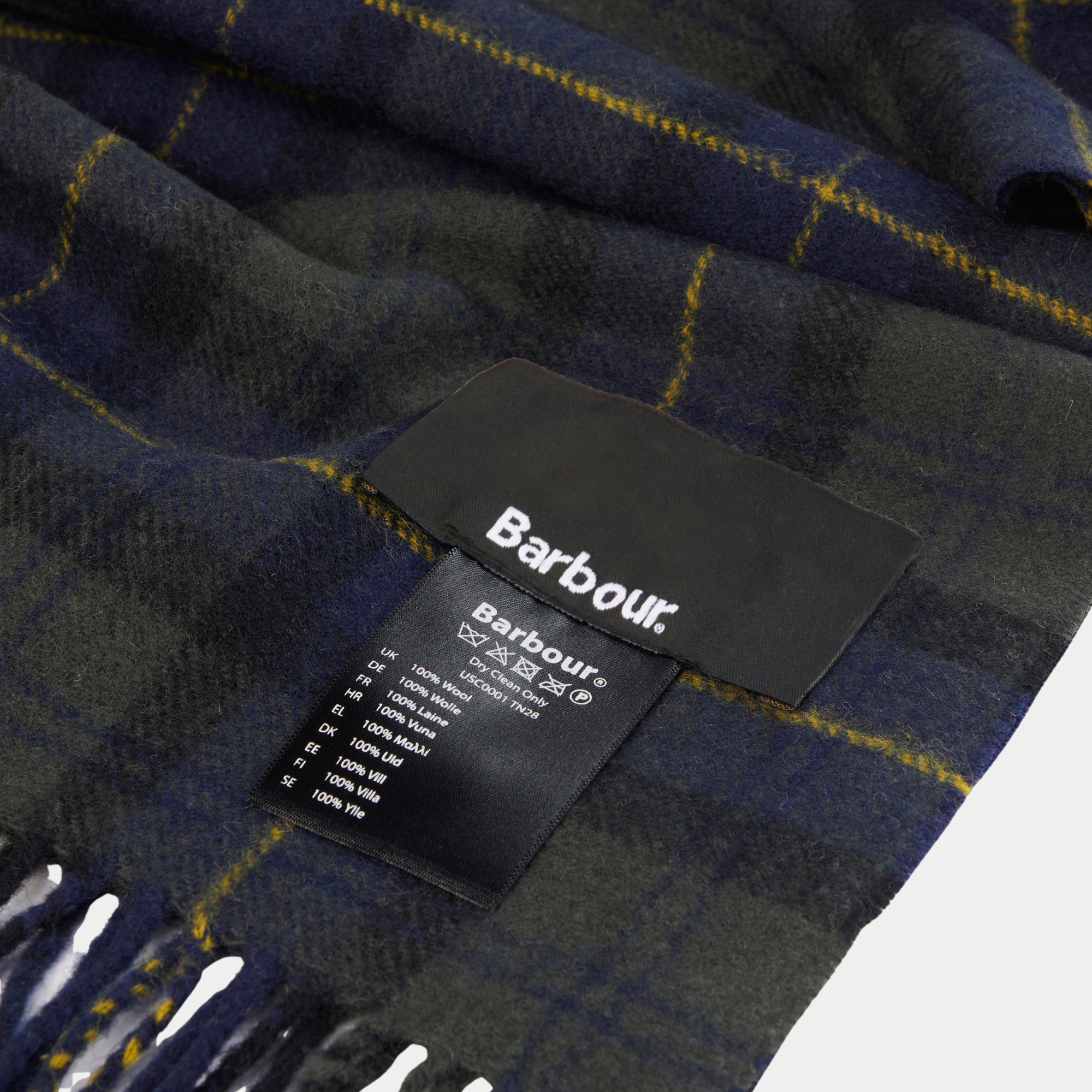 Étiquettes Barbour et composition 100 % laine sur le tartan vert foncé, marine et jaune de l’écharpe.