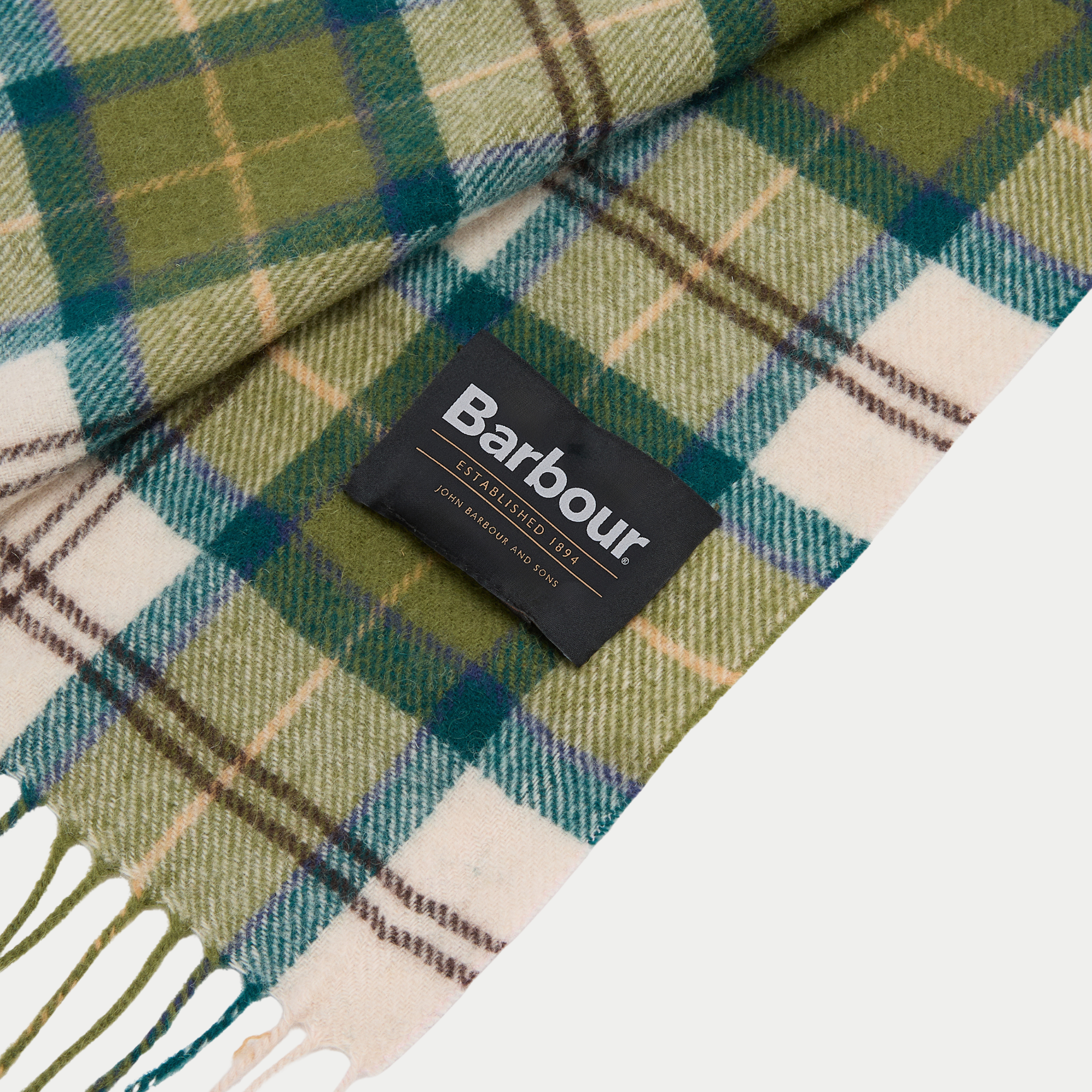 Étiquette tissée Barbour sur l'écharpe tartan vert mousse, gros plan sur le tissage laine et les franges