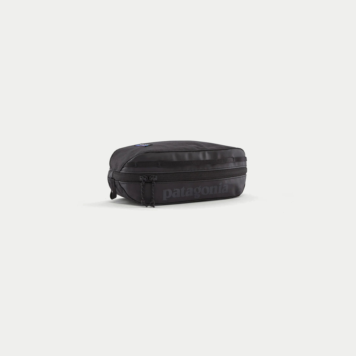 Cube Black Hole 3L noir Patagonia, trois quarts avant : logo ton sur ton, zip double curseur et sangle daisy chain