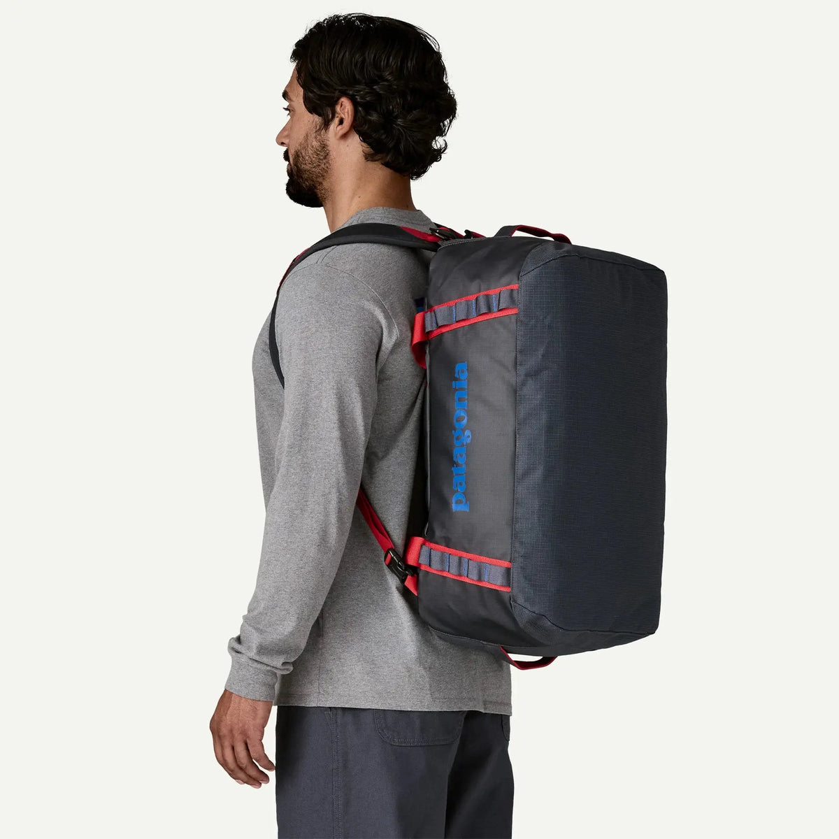 Black Hole Duffel 40L Smolder Blue porté en sac à dos, sangles rouges croisées dans le dos