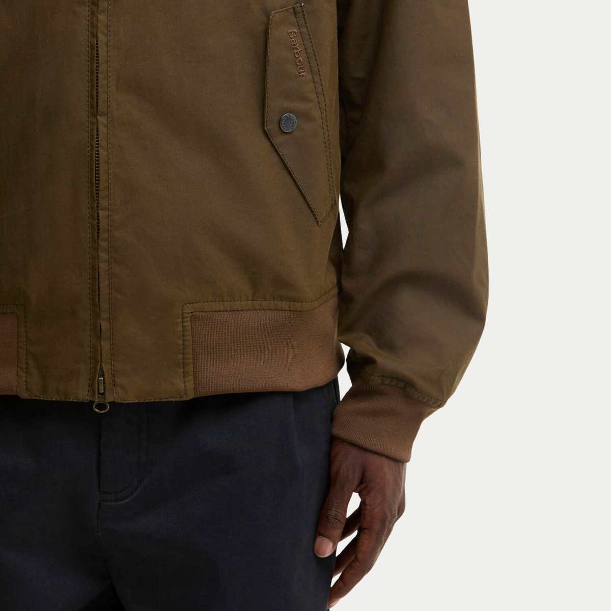 Détail du blouson ciré Chelsea marron Barbour : rabat de poche brodé ton sur ton, pression métal et bord-côte camel