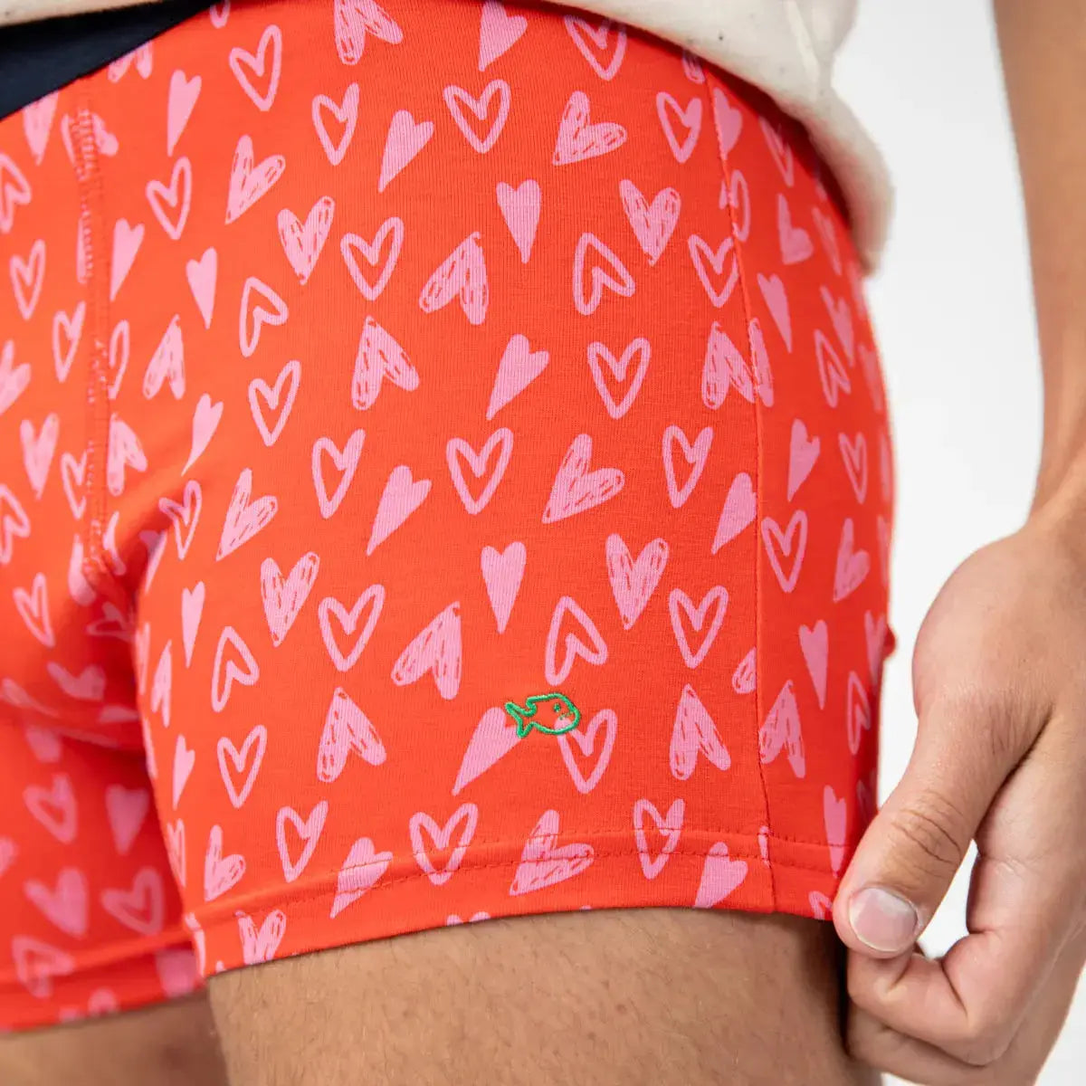Détail du boxer Valentin : poisson brodé vert sur la jambe, cœurs roses esquissés sur fond rouge orangé