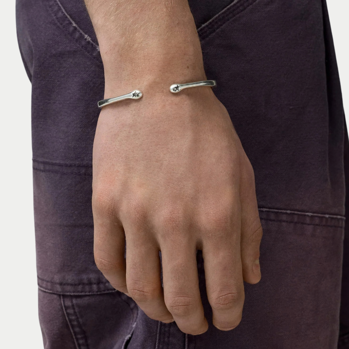 Bracelet jonc 01 Twojeys porté au poignet, embouts arrondis frappés d'une étoile
