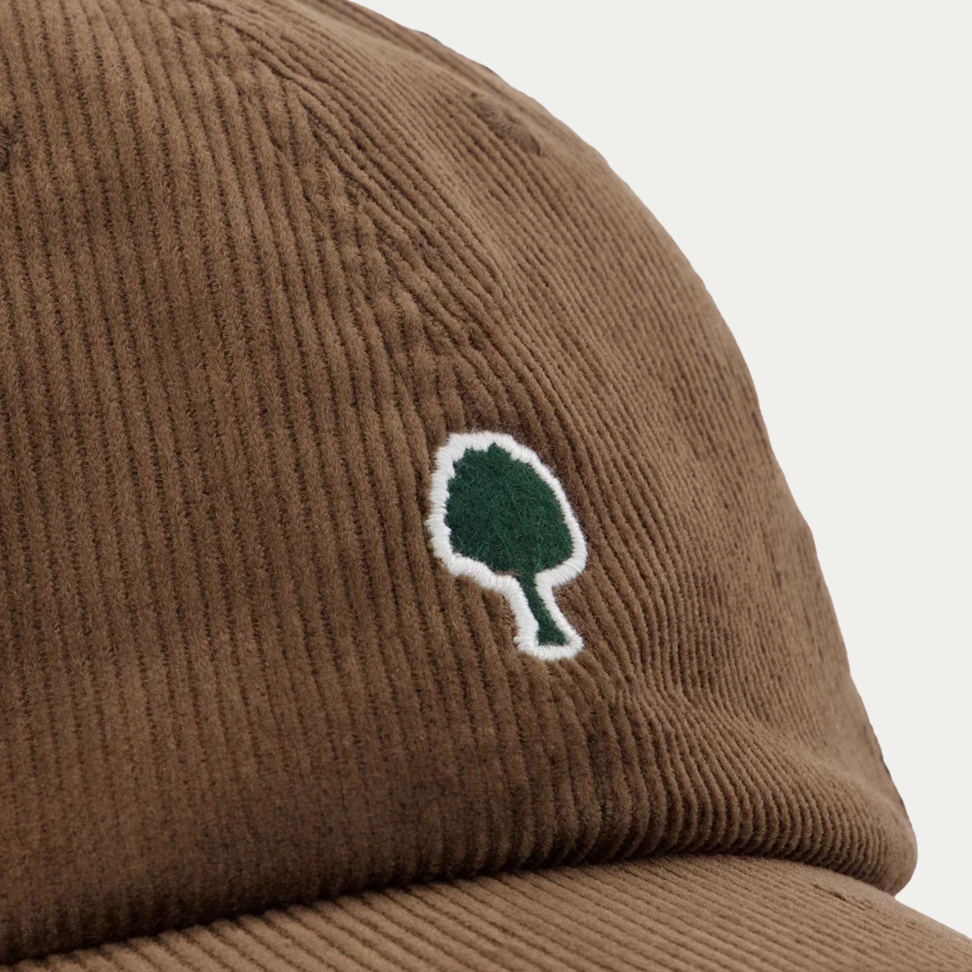 Détail macro du velours côtelé chocolat de la casquette Faguo et de la broderie arbre verte bordée de blanc