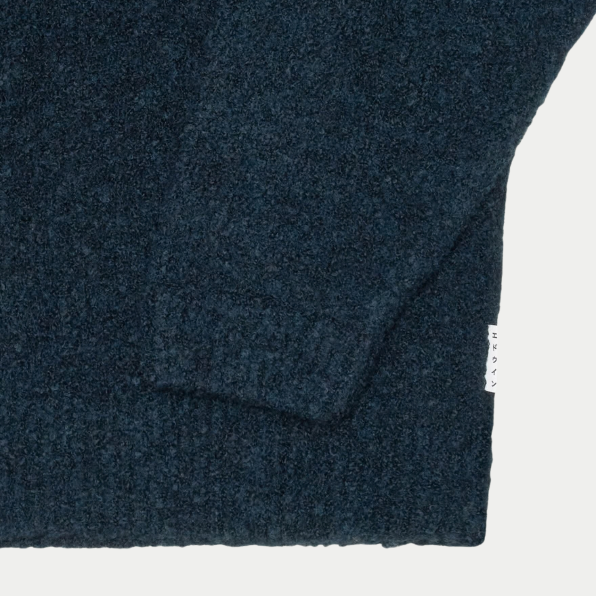 Gros plan sur la maille bouclette chinée, le poignet et l’ourlet côtelés du cardigan Gemini bleu marine