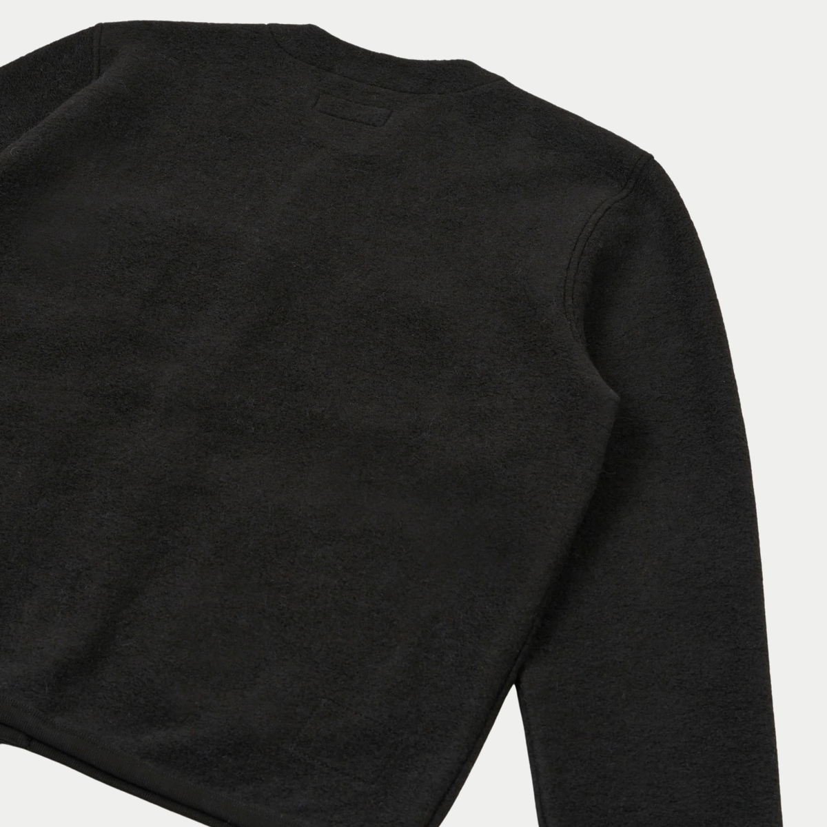 Dos du cardigan en Wool Fleece noir à plat, petite étiquette sous l'encolure et couture d'emmanchure