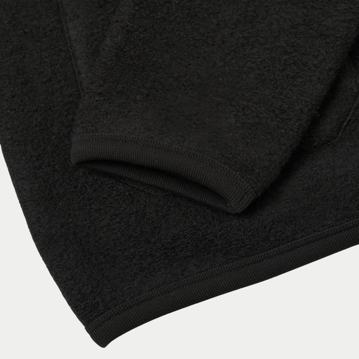 Poignet et ourlet du cardigan en Wool Fleece noir Universal Works bordés de côtes fines en coton