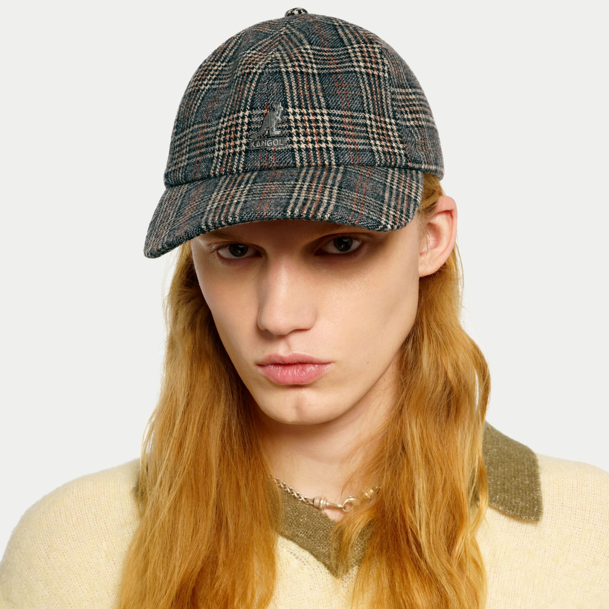 Casquette Kangol à carreaux gris portée de face, rabats repliés, logo kangourou sur le panneau avant
