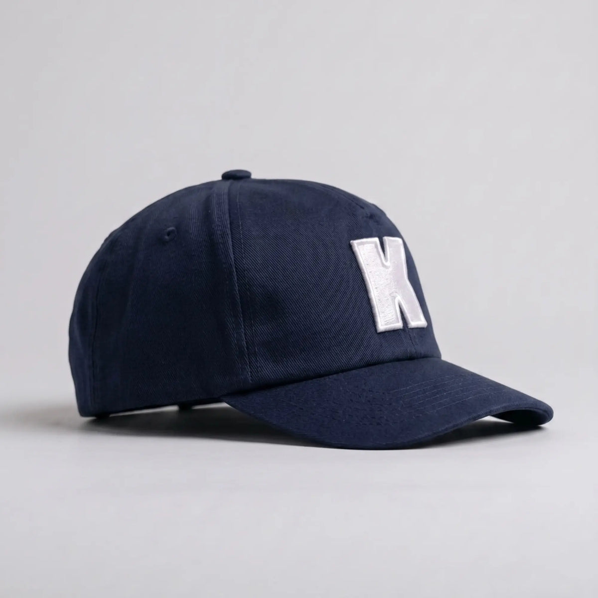 Casquette Klubb marine de trois-quarts : calotte souple sans armature, œillet d'aération brodé et visière longue à surpiqûres