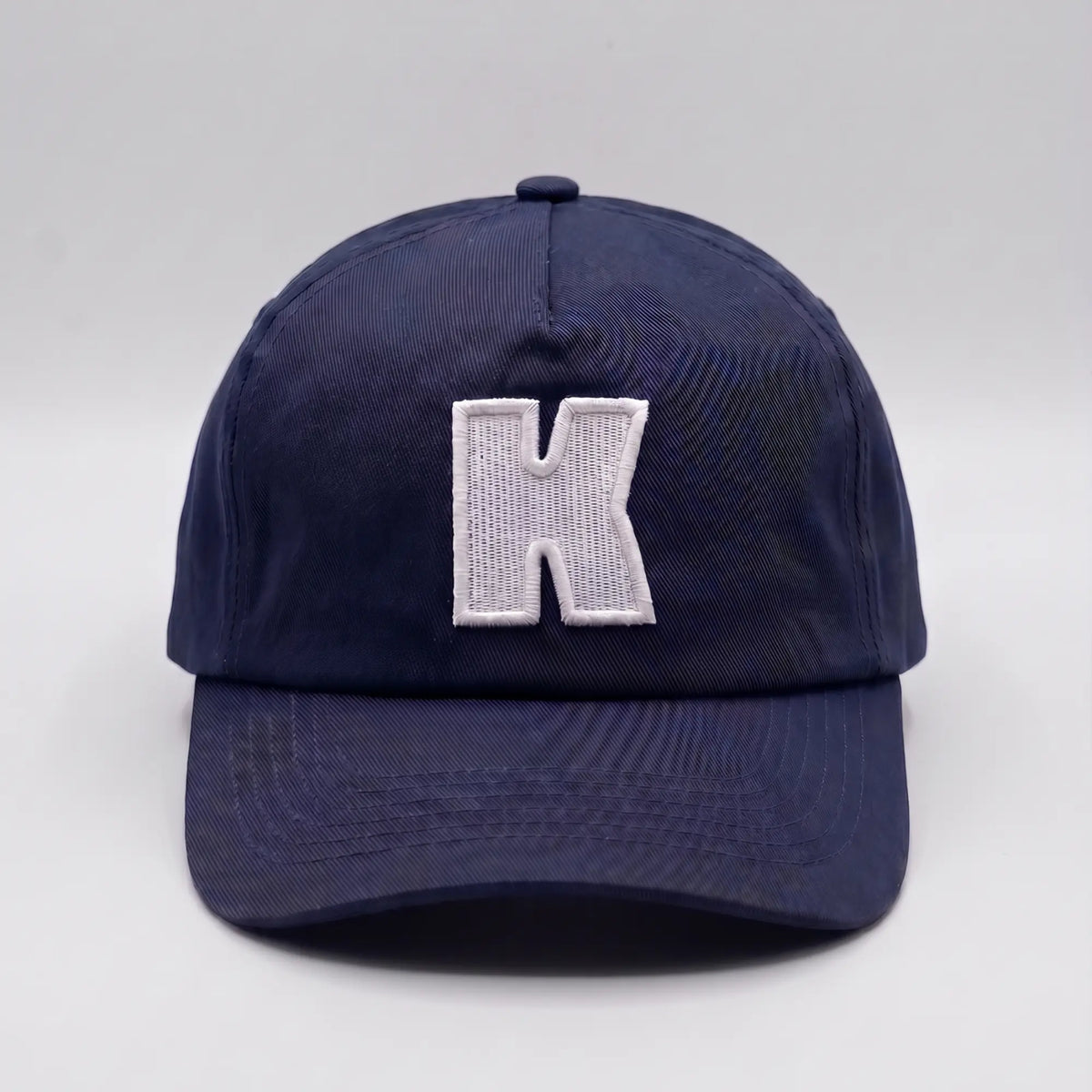 Casquette baseball Klubb bleu marine vue de face, K blanc brodé en relief au centre de la calotte souple