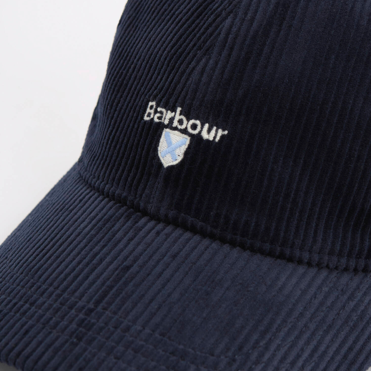 Détail brodé du logo Barbour et de son écusson bleu ciel sur le velours à grosses côtes de la casquette Preston