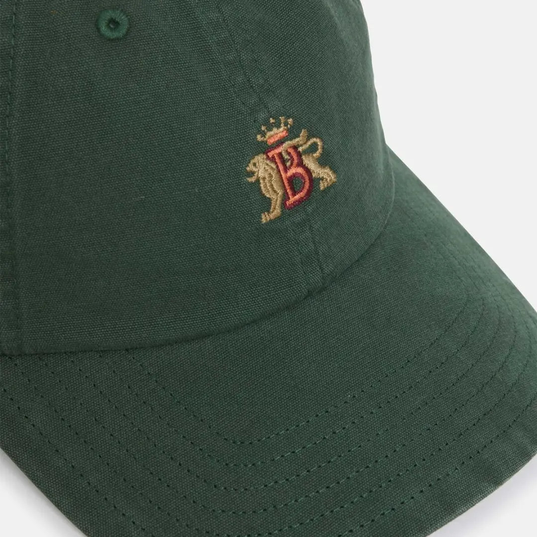 Gros plan packshot : broderie B couronnée aux lions dorés sur la toile de coton vert sapin