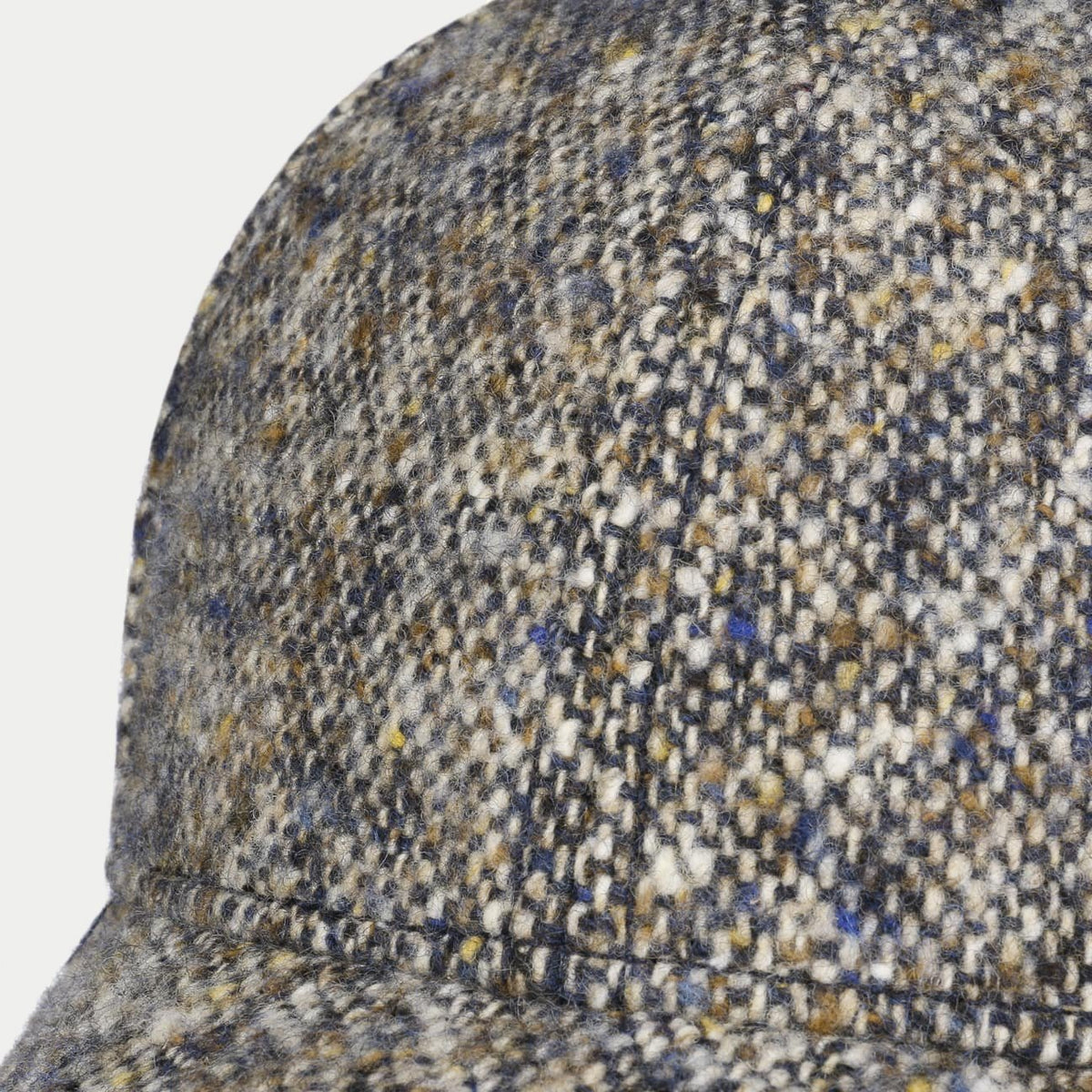 Gros plan du tweed Donegal beige moucheté de bleu, d'ocre et d'écru sur la calotte, casquette Stetson