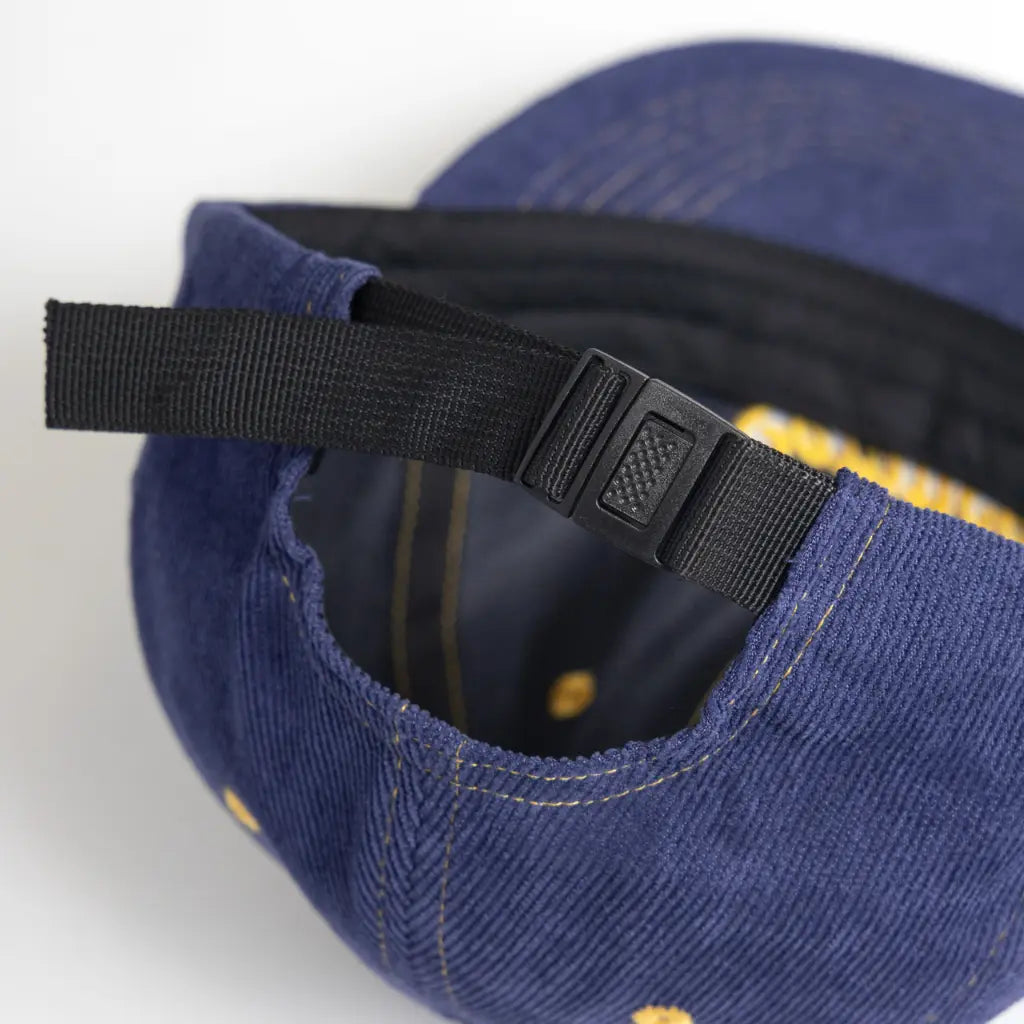 Sangle de serrage noire à boucle plastique à l'arrière de la casquette en velours bleu marine