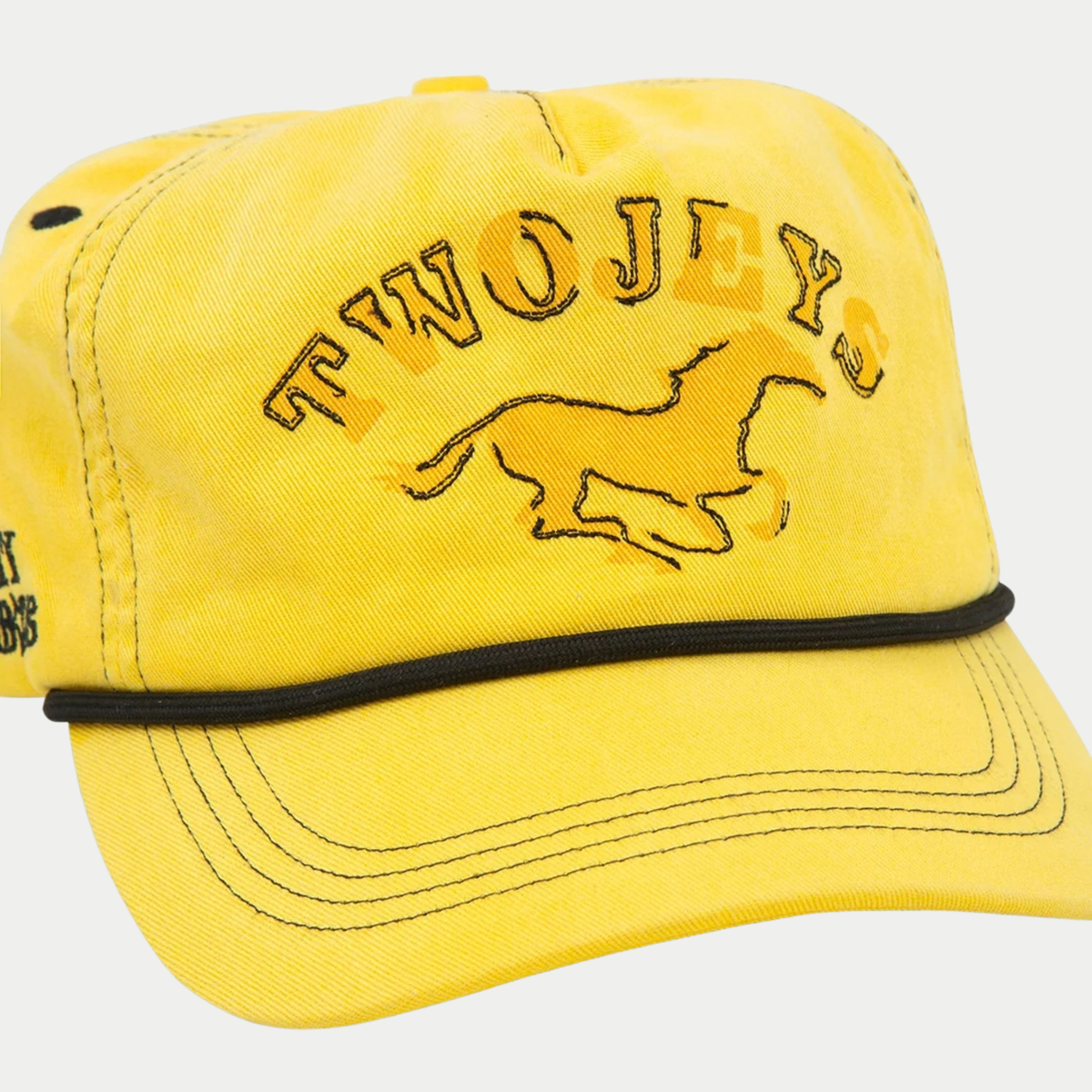 Gros plan sur la broderie cheval TWOJEYS et le cordon noir de la casquette délavée jaune