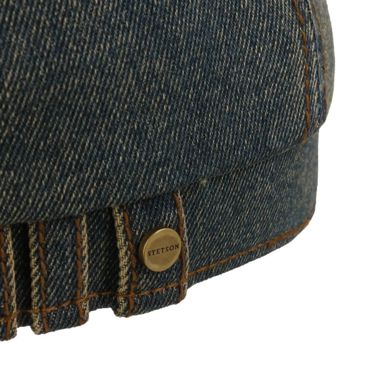 Gros plan du bouton laiton gravé et des plis de denim à l'arrière