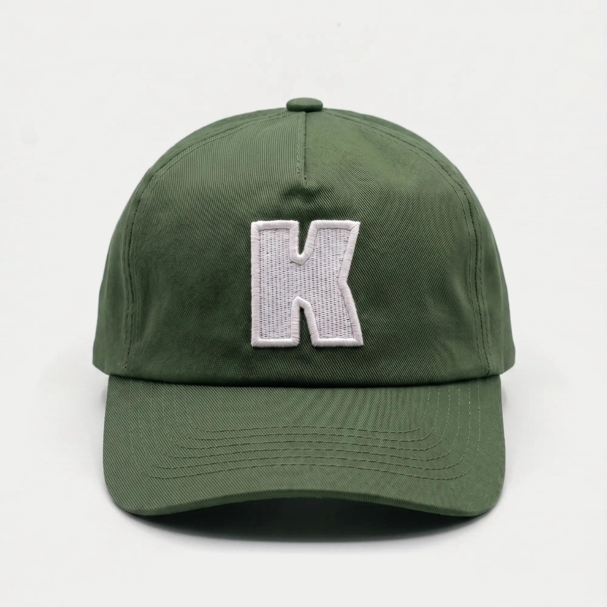 Casquette baseball Klubb vert olive grisé vue de face, grand K blanc brodé au centre du panneau avant et visière courbée