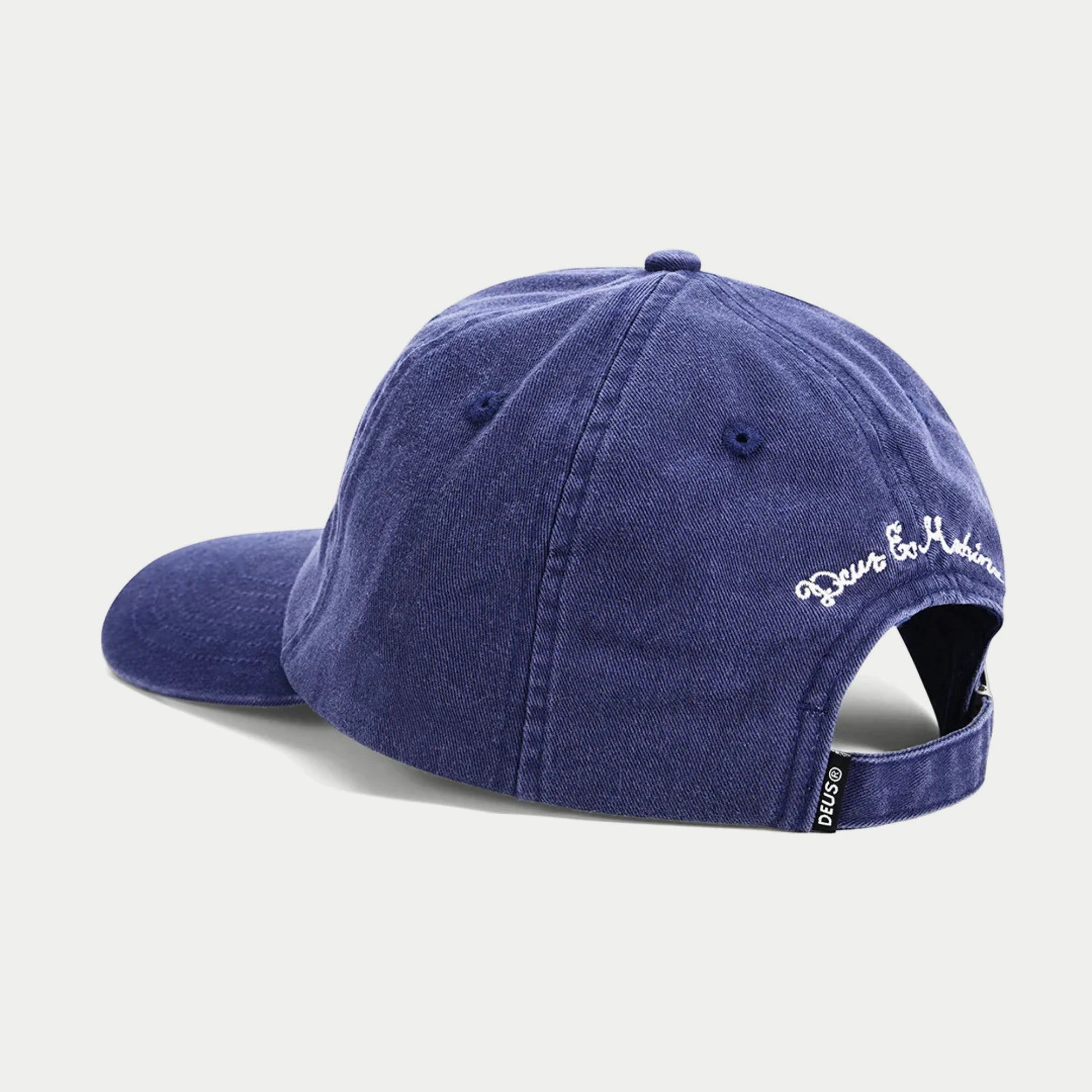Casquette Metro indigo Deus Ex Machina vue de dos : patte de réglage en sergé et signature cursive brodée blanche sur le côté