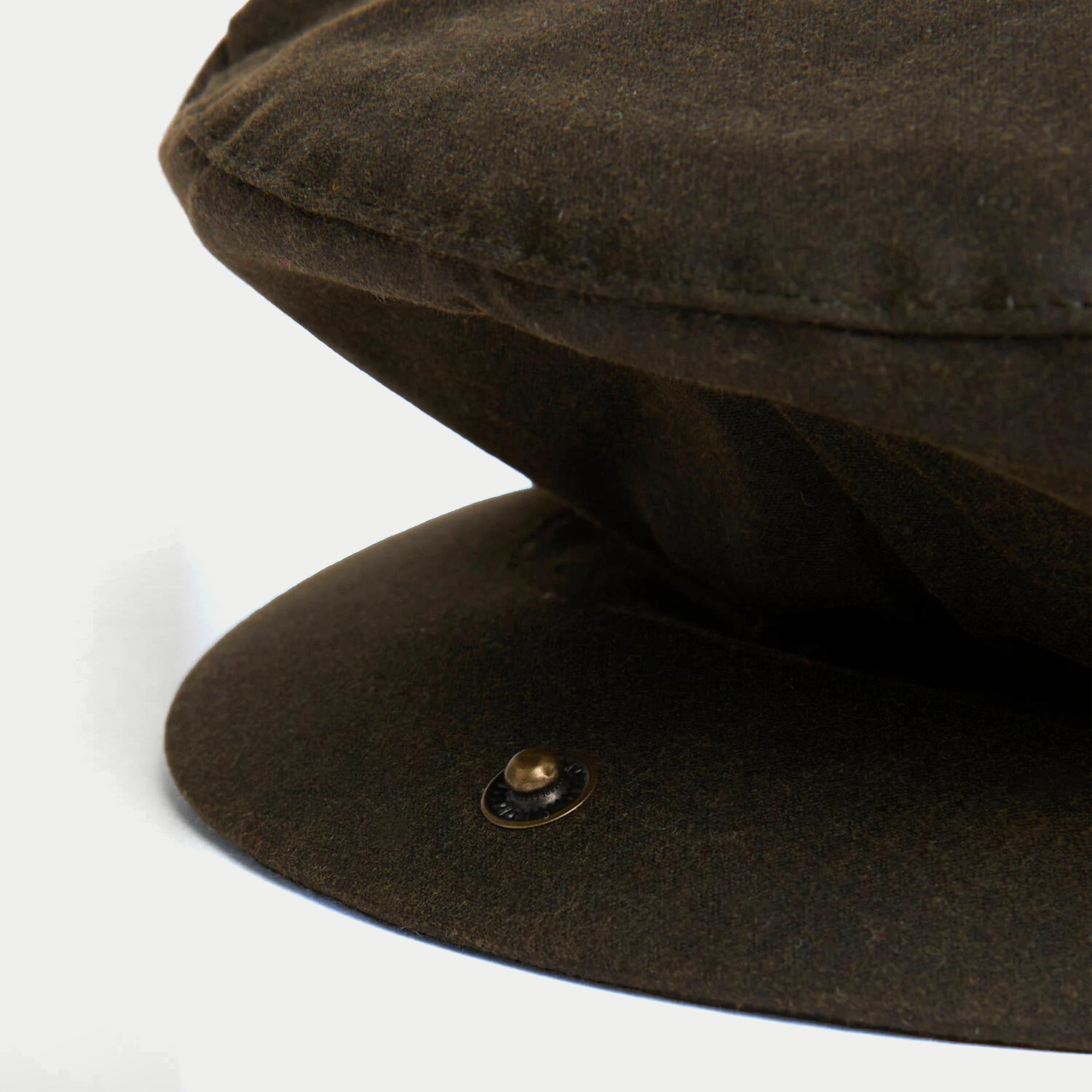 Casquette plate cirée olive Barbour - gros plan sur la visière et le bouton pression laiton