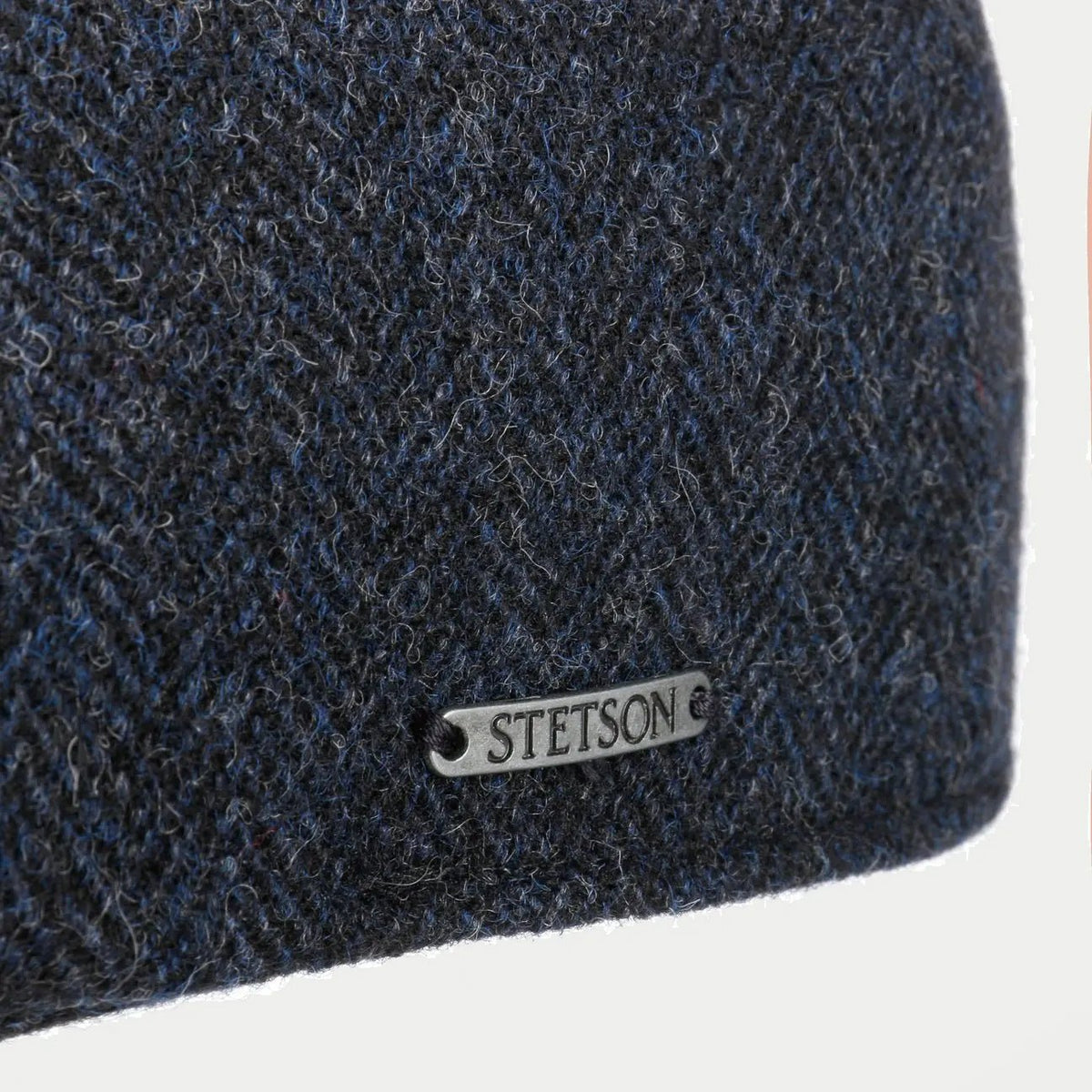 Détail macro de la laine à chevrons bleu marine et du badge métal Stetson de la casquette Texas