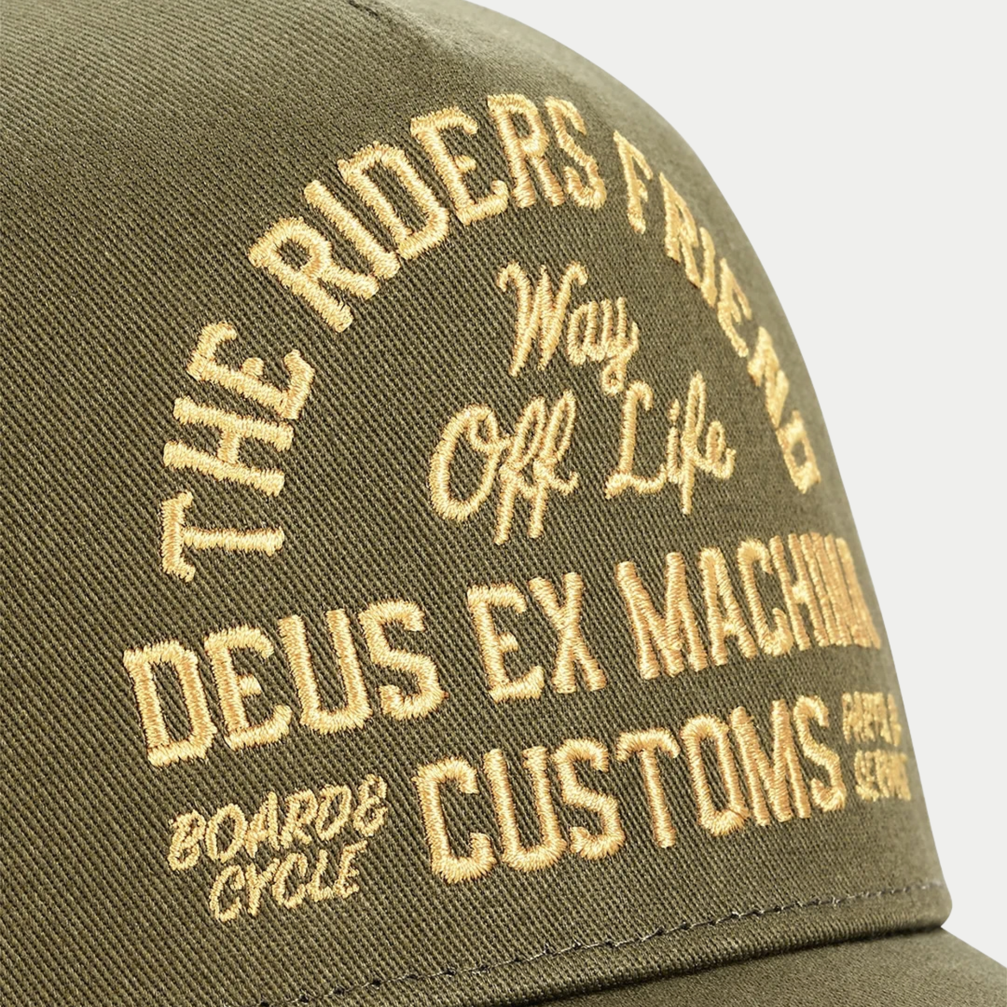 Détail de la broderie dorée Deus Ex Machina Customs sur le twill olive de la casquette Shook Ones