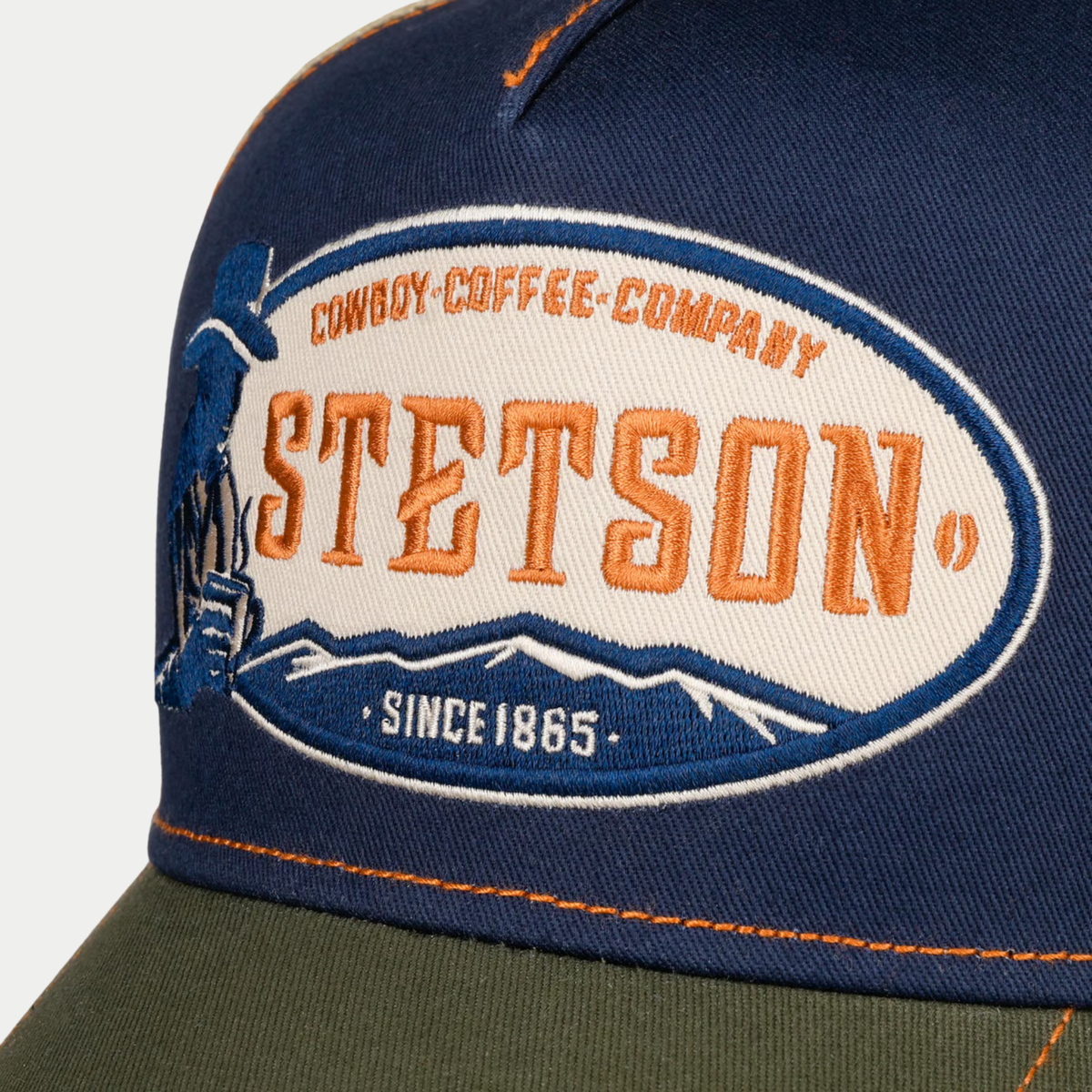 Gros plan de l'écusson brodé Stetson Cowboy Coffee Company Since 1865, cowboy et montagnes, sur le devant bleu marine