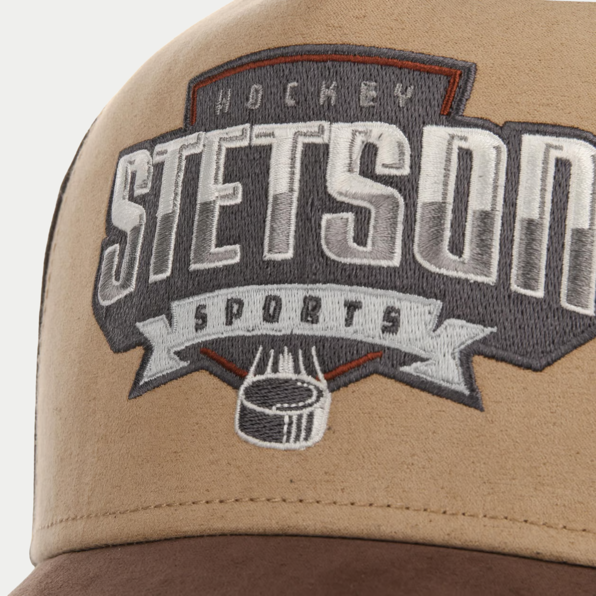 Gros plan sur la broderie Hockey Stetson Sports avec palet, sur le devant beige en suédine de la casquette