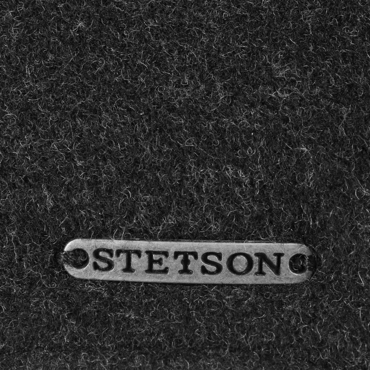 Gros plan sur la plaque métal Stetson et la laine chinée gris anthracite de la casquette Vaby
