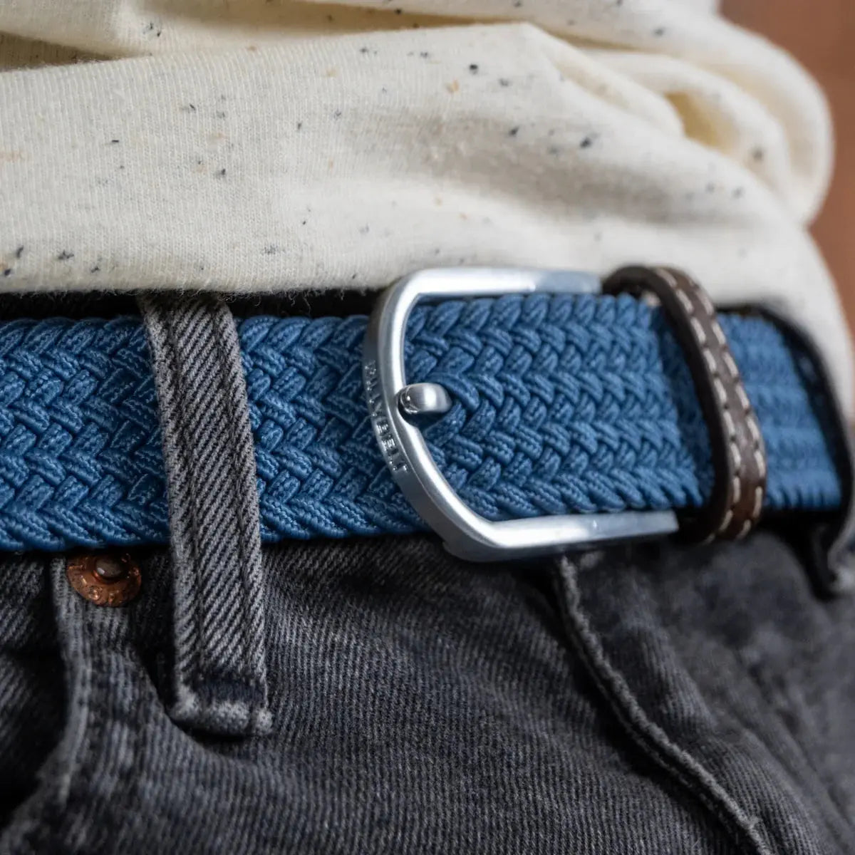 Gros plan sur la boucle argent brossé gravée BILLYBELT, serrée sur le tressage bleu jean Bleu Air Force