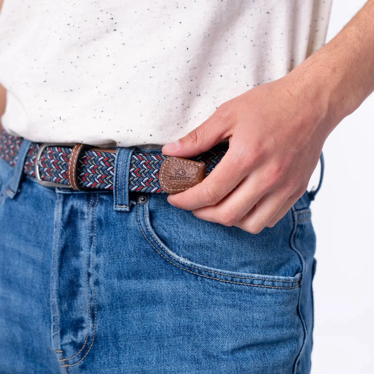 Ceinture Istanbul aux fils bleu marine, bleu jean, rouge et blanc portée sur un jean clair, embout de cuir marron