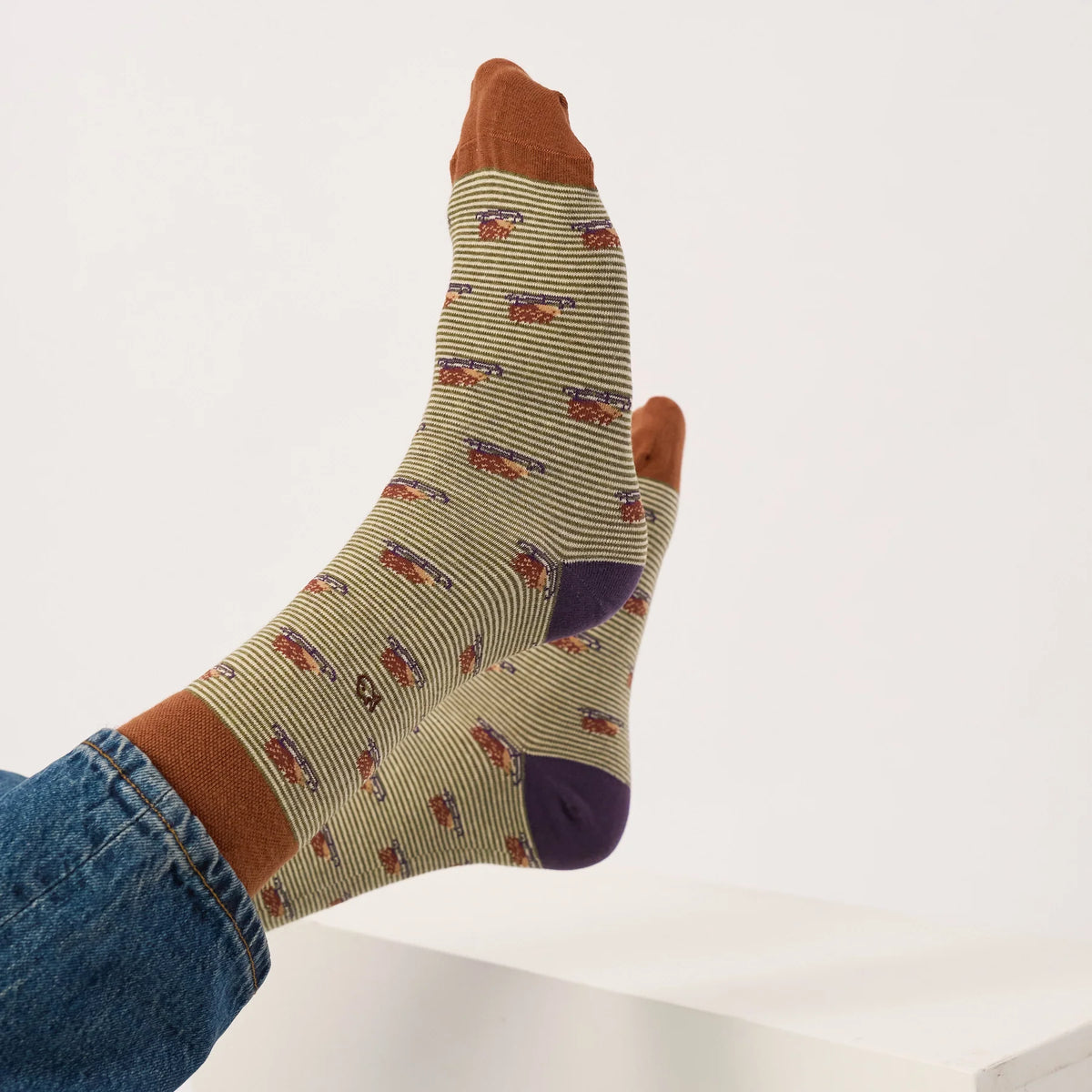 Chaussettes Hérisson BillyBelt portées jambes croisées sous un jean retroussé, pointes marron et talons violets