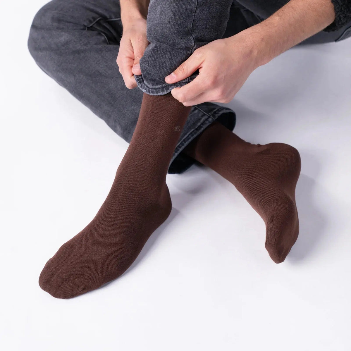 Paire marron en bambou portée assis, jambes croisées sous un jean gris remonté, pointe et talon bien visibles