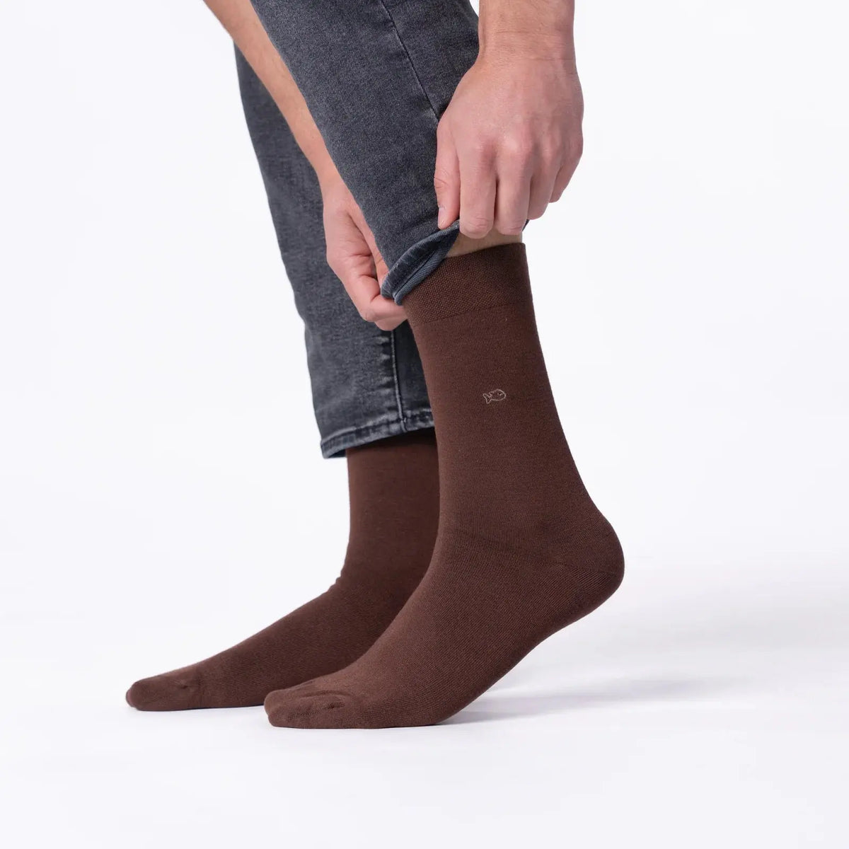 Chaussettes marron en bambou portées debout de profil, tige mi-mollet unie et petit poisson brodé clair