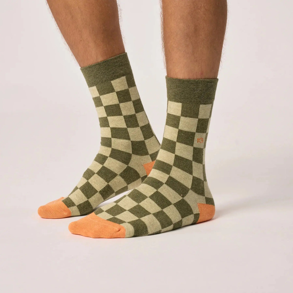 Chaussettes à carreaux kaki et vert clair portées de profil, pointes orange et poisson brodé sur la tige